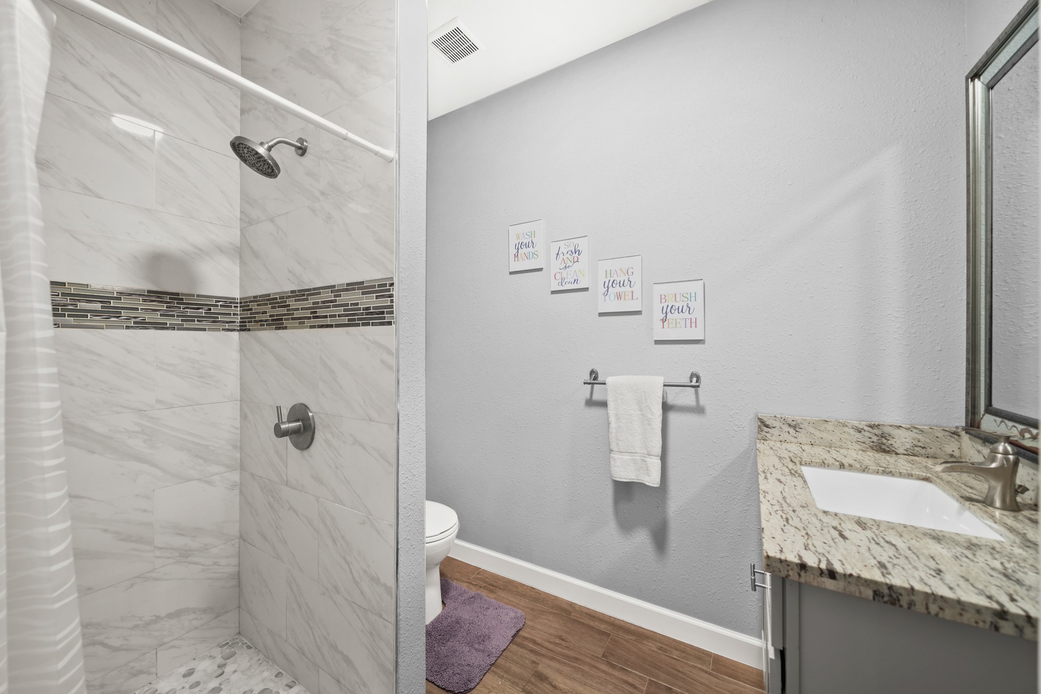 Secondary Bathroom 1: Highlights the glass shower doors and granite vanity
