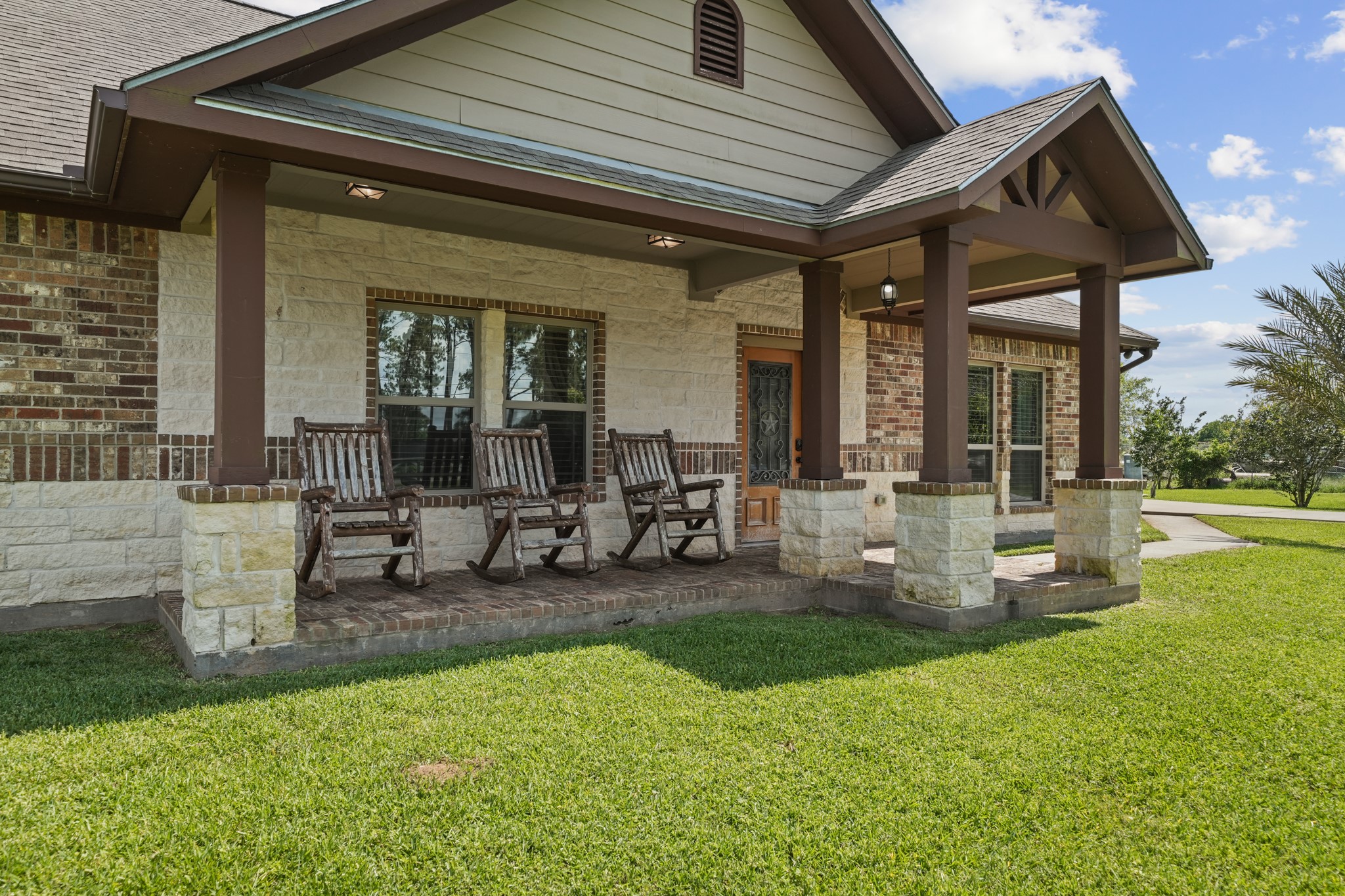 Relax in style on this charming front porch, featuring inviting rocking chairs and elegant stone column details.