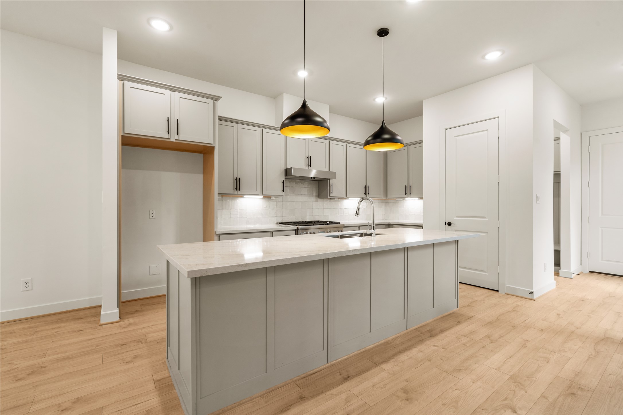 Open-concept kitchen view  fluid connection from the prep island to the main floor landing and adjacent pantry access.
