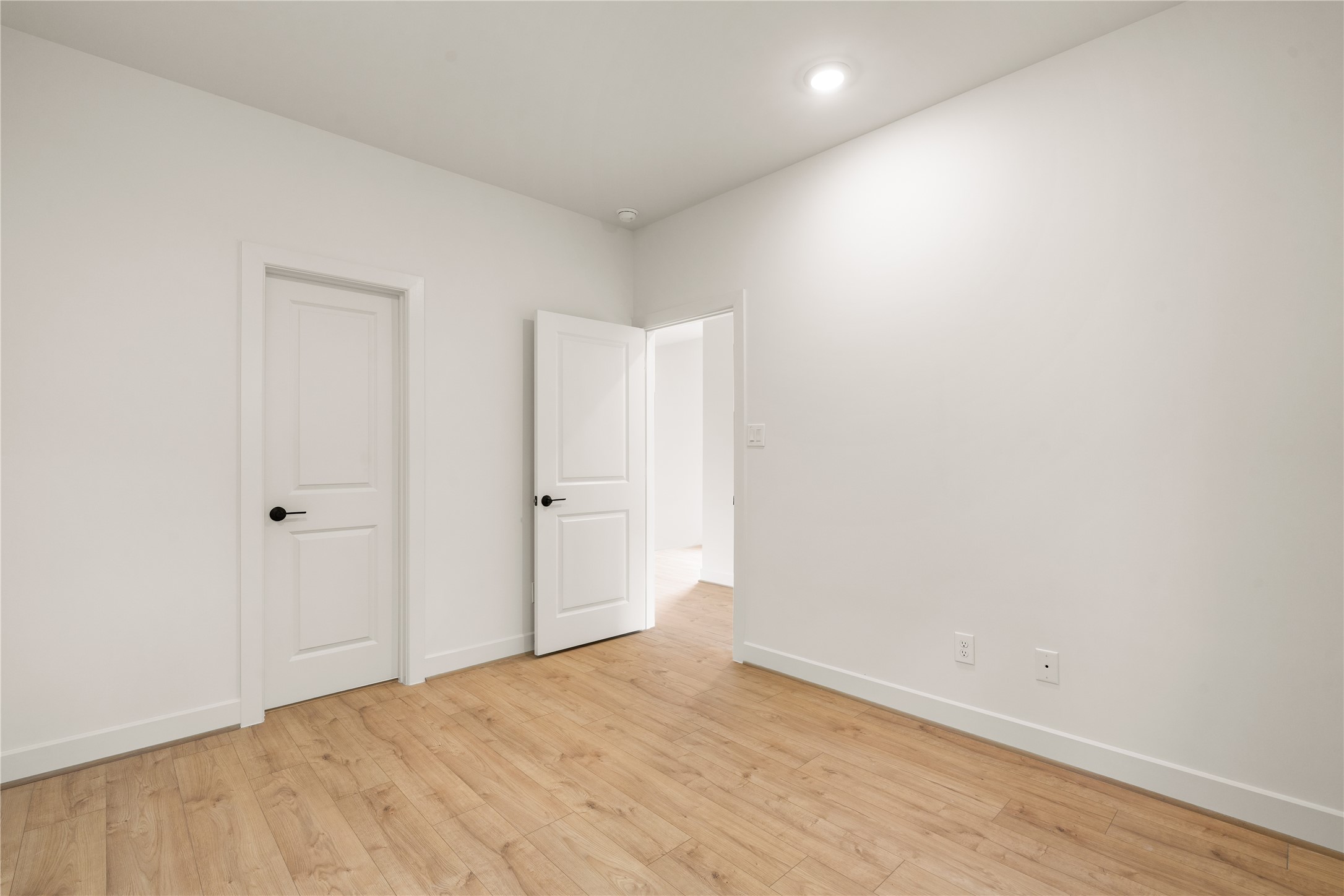 Versatile bedroom space  pre-wired for wall-mounted media, dark door lever accents, and seamless access to private closet storage.