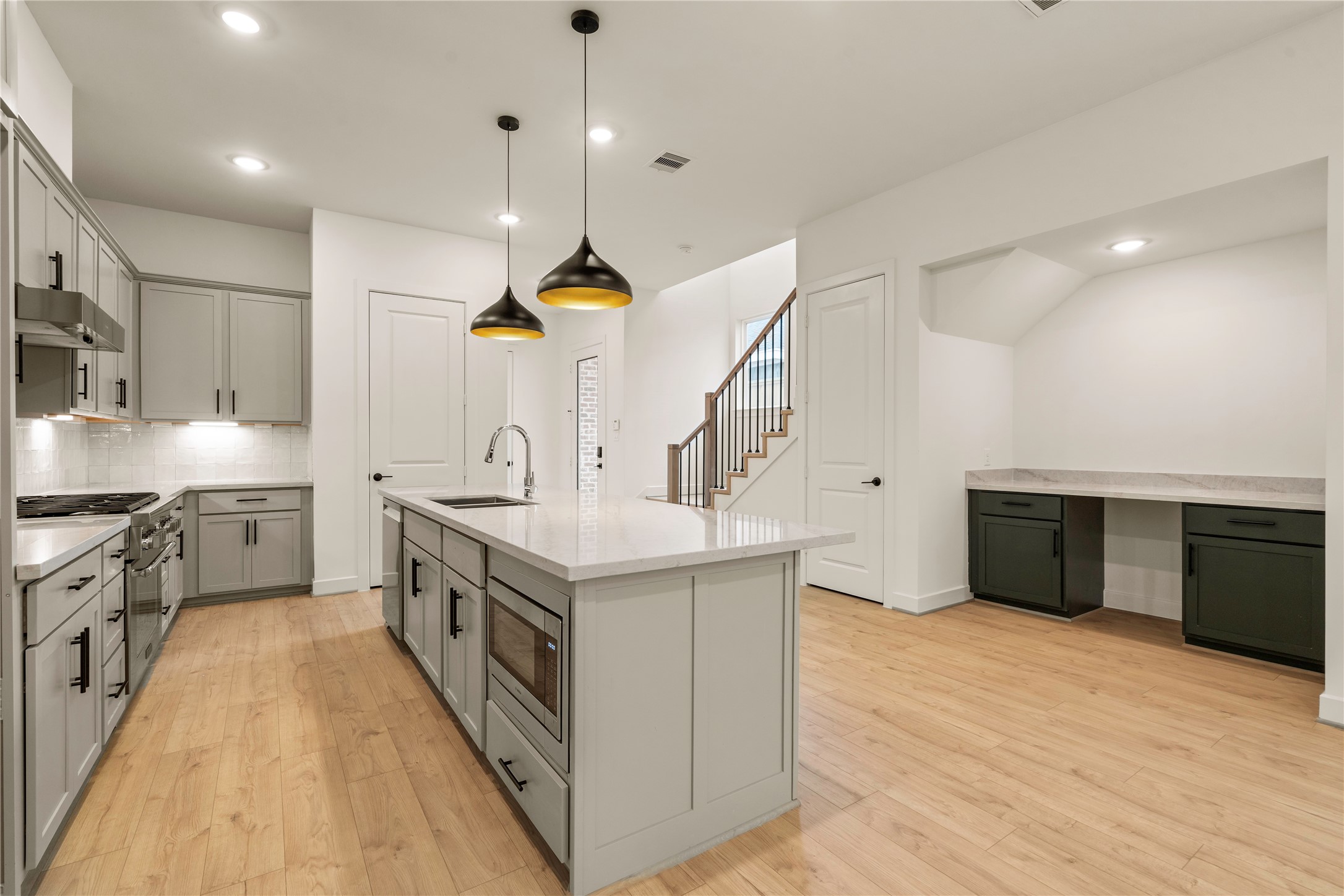 Functional design features  island microwave drawer inset, stainless steel appliance package, and custom built-in workstation nook tucked neatly under the staircase.