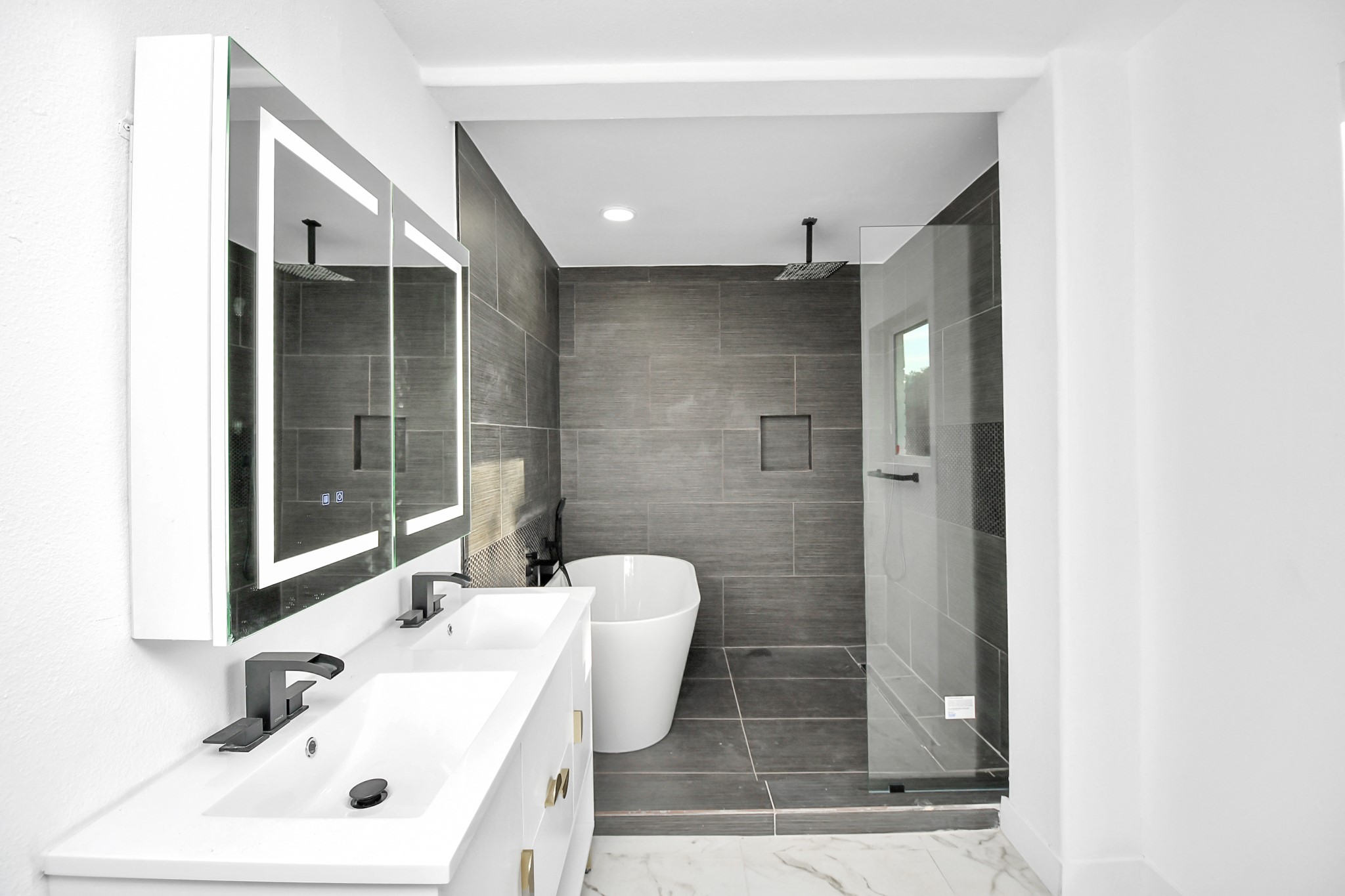 The downstairs bathroom offers every luxury, featuring touch screen smart mirrors, a seamless glass shower, and a freestanding soaking tub, leaving nothing to be desired.