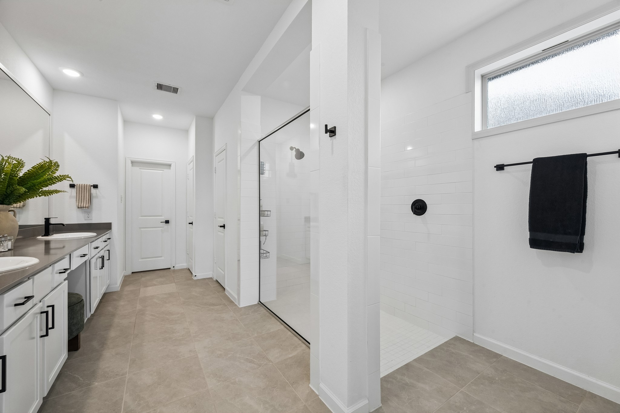 Primary en suite with walk-in shower, dual sinks, vanity and linen closet.