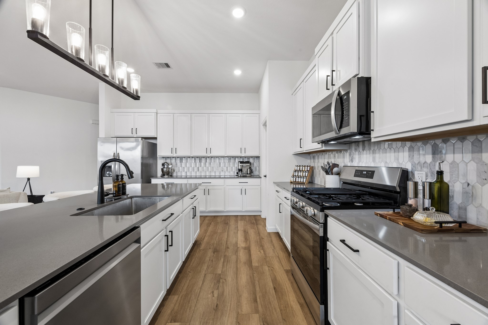 The kitchen color palette is elegant and classic. The new dishwasher intergrates seamlessly with the stainless steel appliances, charcoal quartz countertops and backsplash. The upgrades feature a light fixture over the island sink, and hardware on the cabinets.