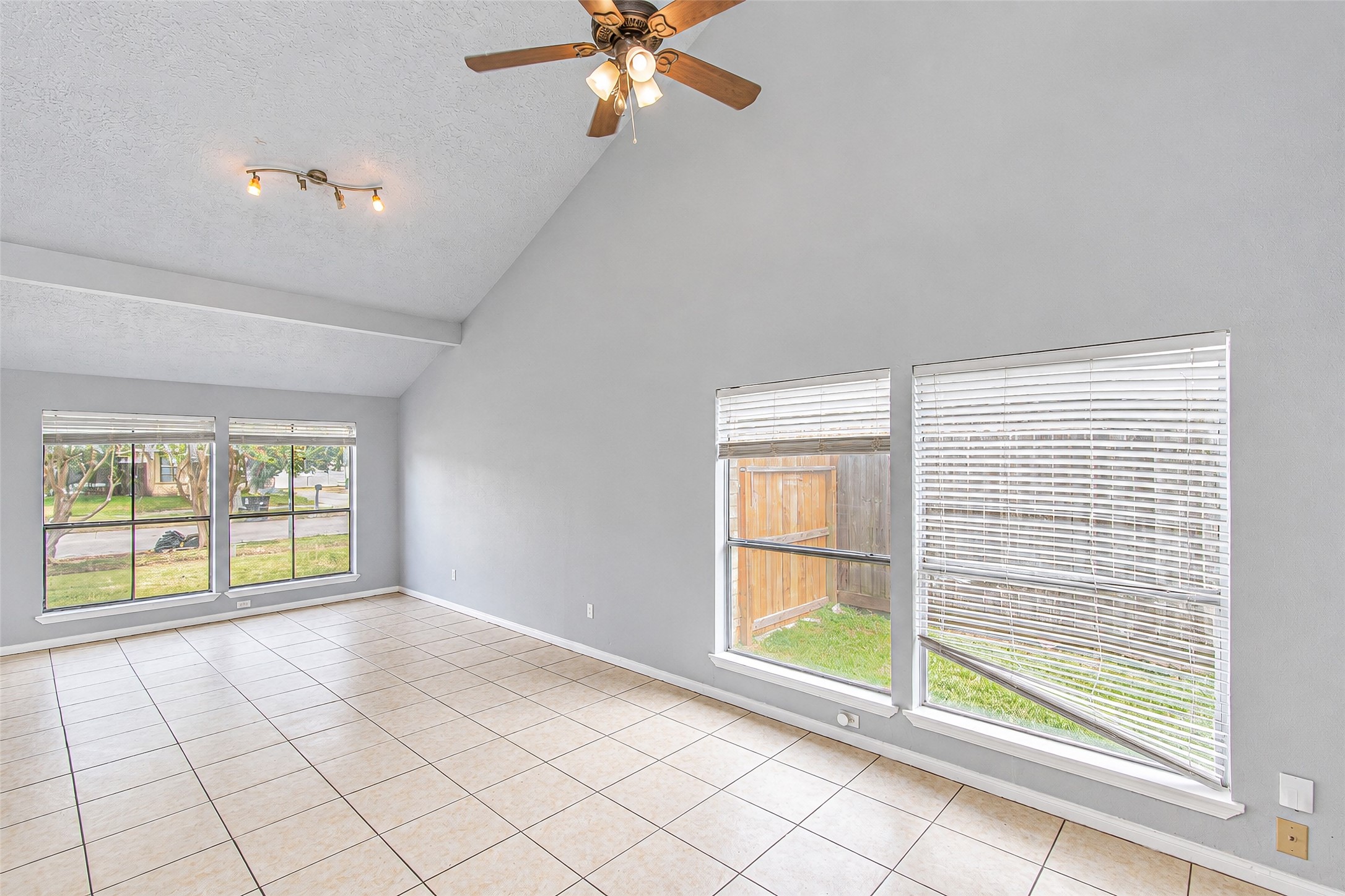 Spacious living room with high vaulted ceilings, abundant natural light from large windows, and elegant tile flooring. Spacious living room with high vaulted ceilings, abundant natural light from large windows, and elegant tile flooring.