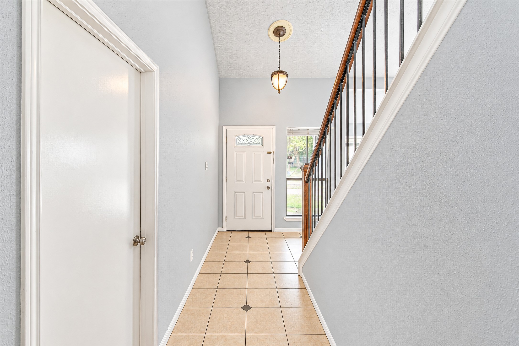 Inviting entryway with high ceilings, elegant tile flooring, and a charming staircase, offering a warm welcome to this beautiful home.