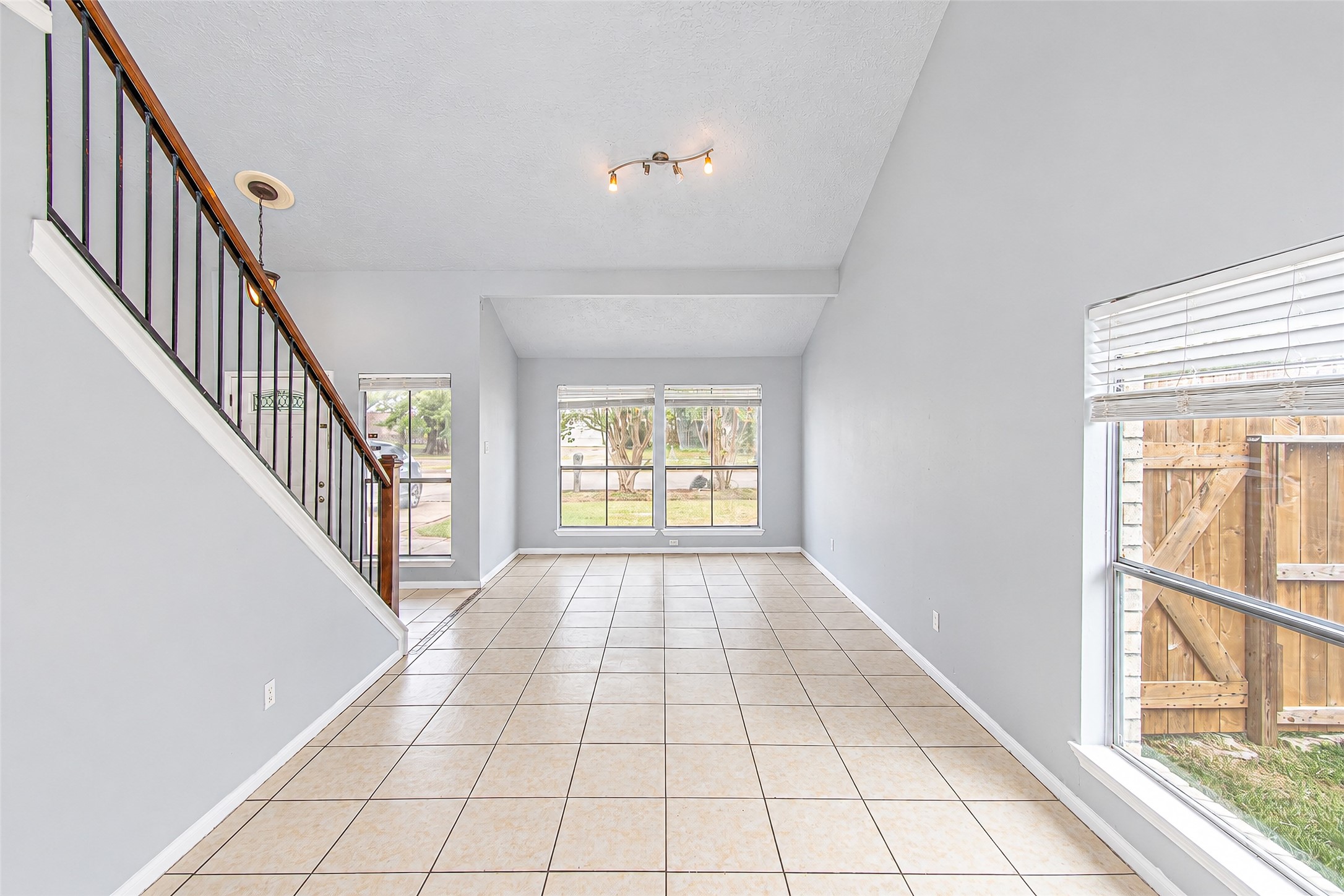 Bright and airy living space with high ceilings, tiled flooring, and large windows offering abundant natural light. Bright and airy living space with high ceilings, tiled flooring, and large windows offering abundant natural light.