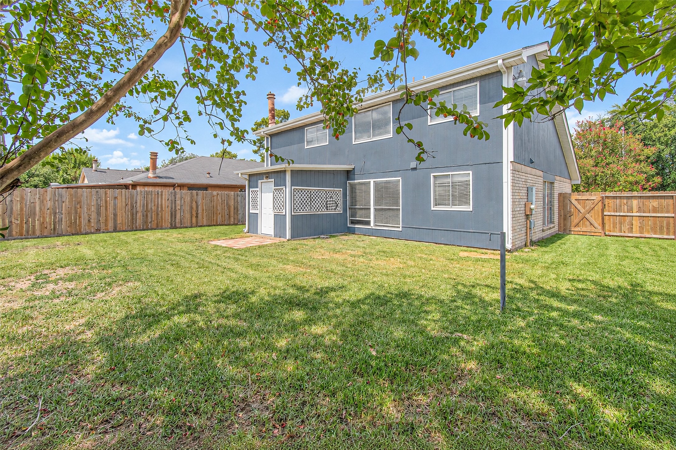 Spacious backyard with lush green lawn and a charming two-story home, perfect for outdoor activities and relaxation.