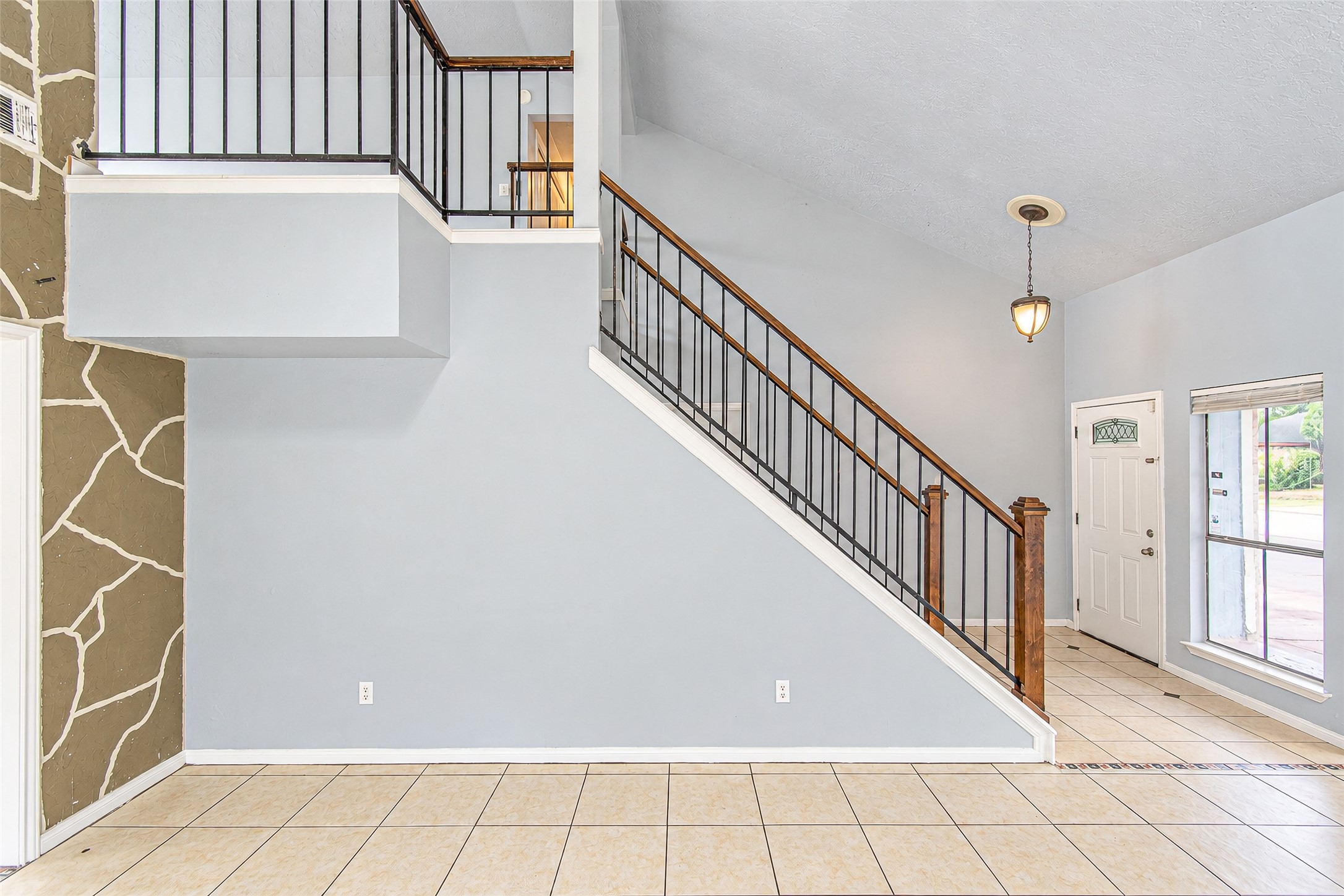 Spacious entryway features a striking staircase with elegant railing, complemented by tiled floors and abundant natural light from large windows. Spacious entryway features a striking staircase with elegant railing, complemented by tiled floors and abundant natural light from large windows.