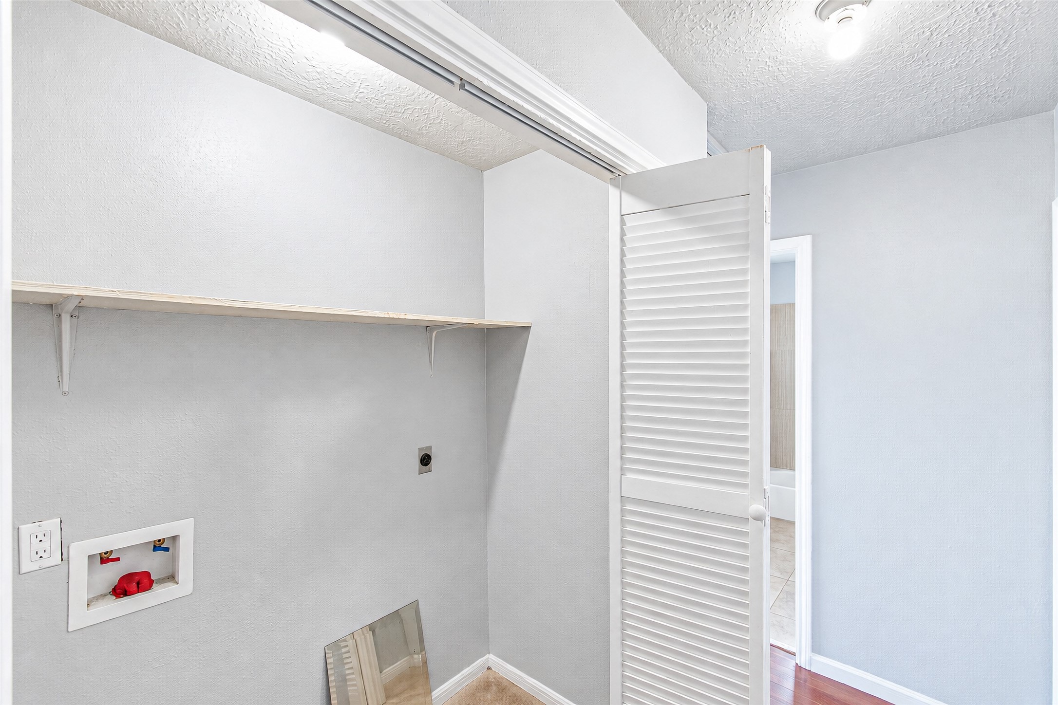 Compact laundry nook with built-in shelving, ready for your washer and dryer setup.
