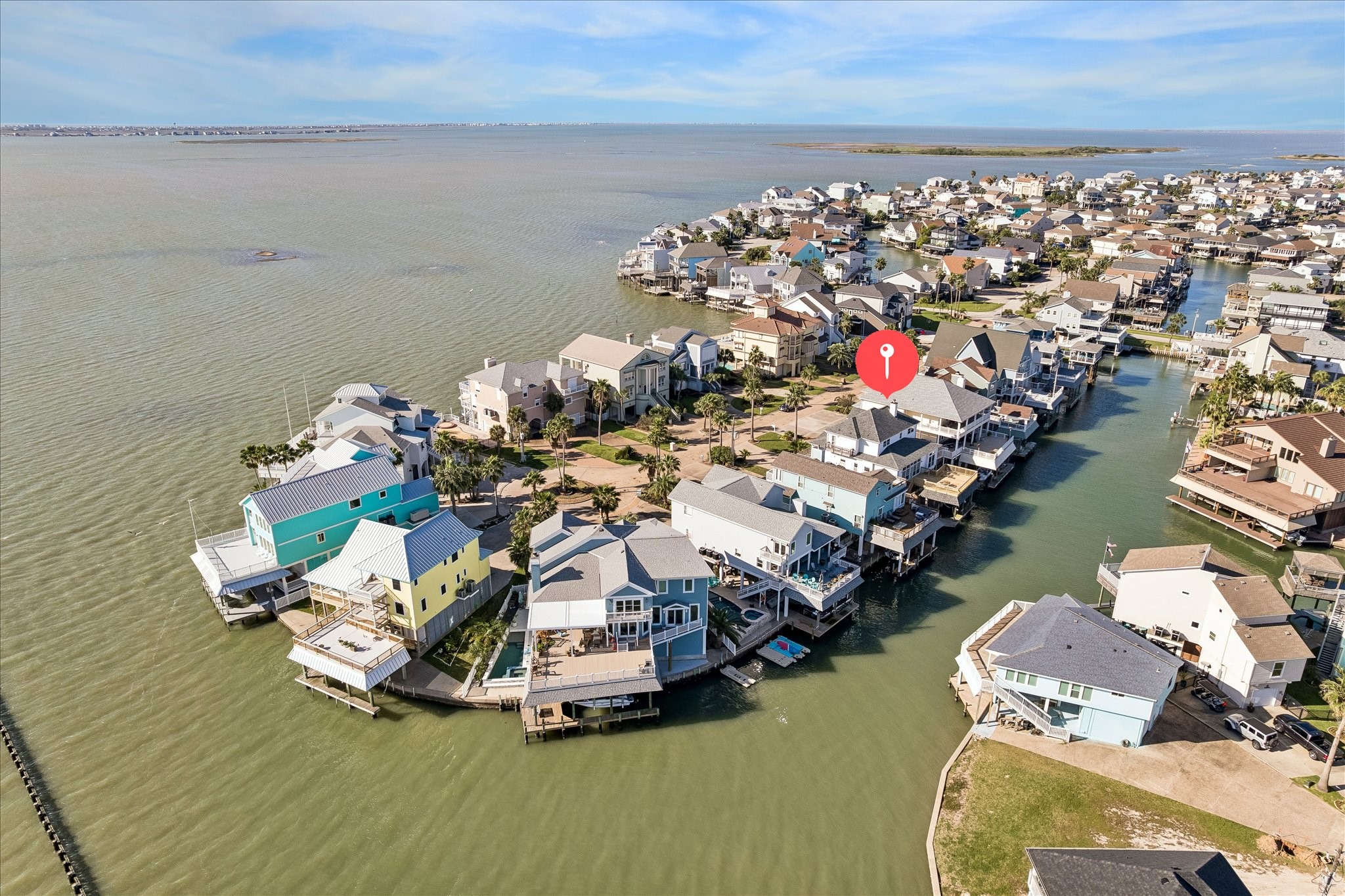 This photo showcases a waterfront community with houses built on stilts along a canal. The neighborhood offers direct water access and scenic views, ideal for boating enthusiasts.