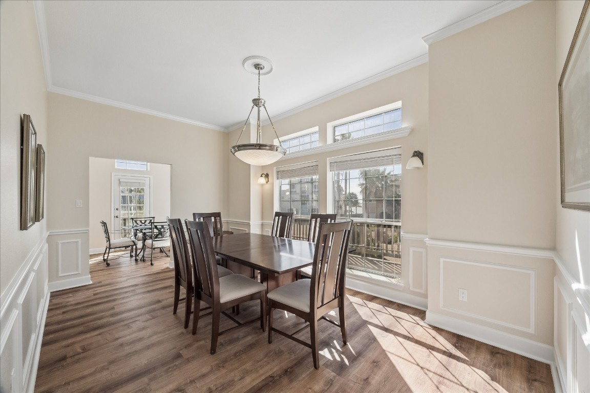 This photo showcases a bright, spacious dining area with large windows, letting in ample natural light. The room features elegant wainscoting, a modern chandelier, and hardwood floors, creating a warm and inviting atmosphere. Adjacent is a cozy breakfast nook, enhancing the home's charm.