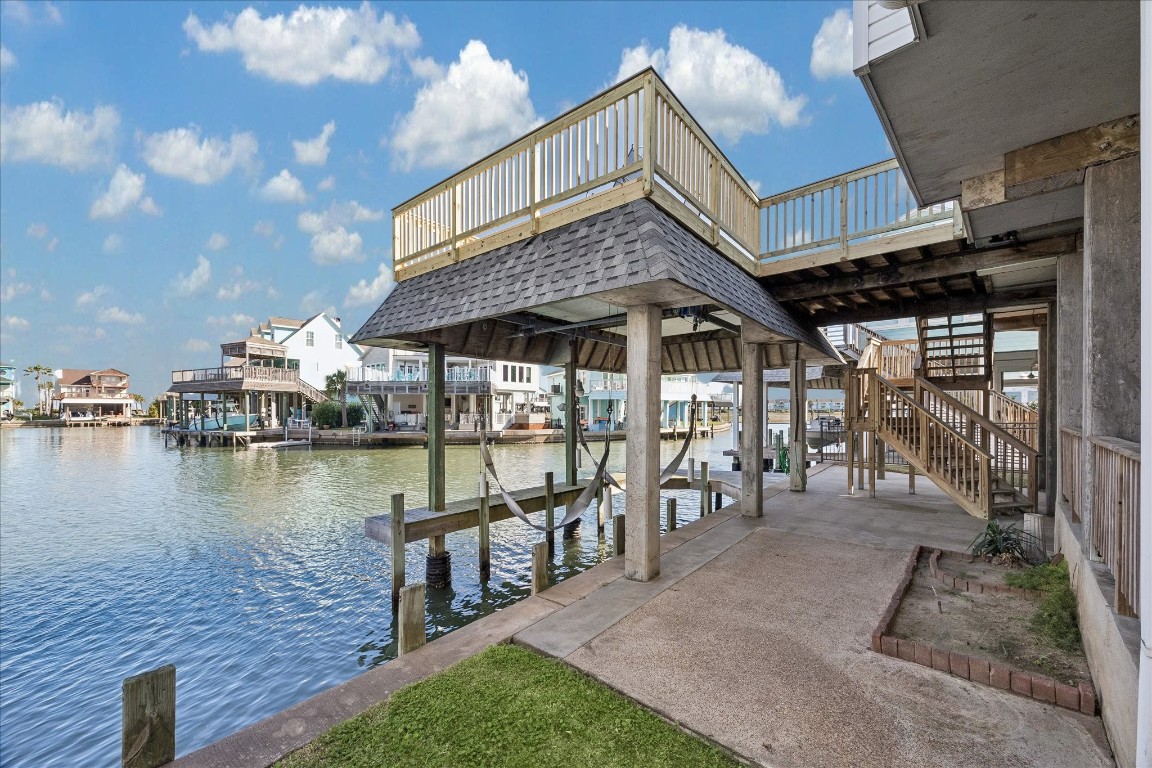 This photo showcases a waterfront property with a spacious dock and upper-level deck, offering scenic views of the canal and surrounding homes. Ideal for boating enthusiasts and those seeking a tranquil waterside lifestyle.