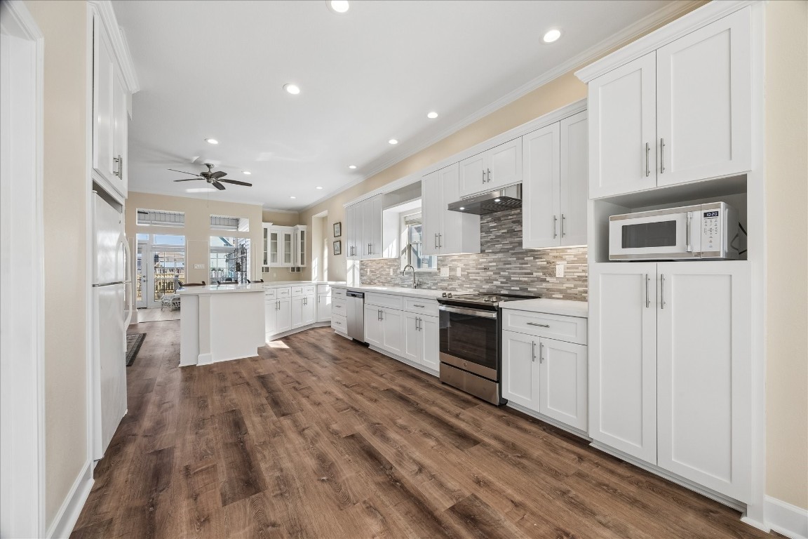 This spacious kitchen features modern white cabinetry, stainless steel appliances, and a stylish tile backsplash. It has a light, open layout with wood-style flooring, ample counter space, and abundant natural light. This spacious kitchen features modern white cabinetry, stainless steel appliances, and a stylish tile backsplash. It has a light, open layout with wood-style flooring, ample counter space, and abundant natural light.