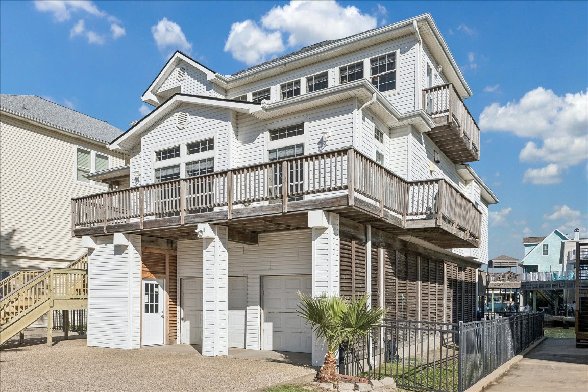 This elevated coastal home features a multi-level design with expansive balconies, a spacious garage, and charming exterior details. Ideal for enjoying waterfront living with plenty of natural light.