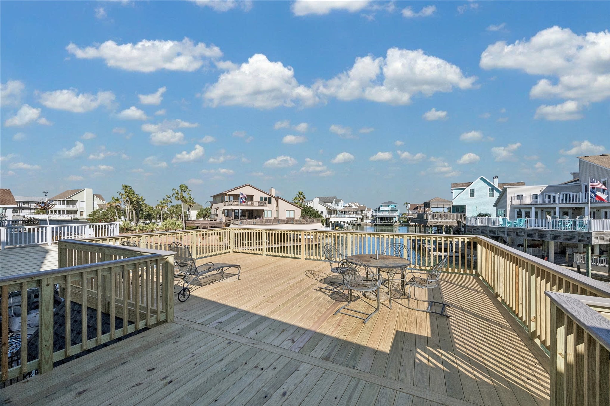 Spacious waterfront deck with wooden railing, perfect for relaxing or entertaining, offering scenic views of a canal and nearby homes.