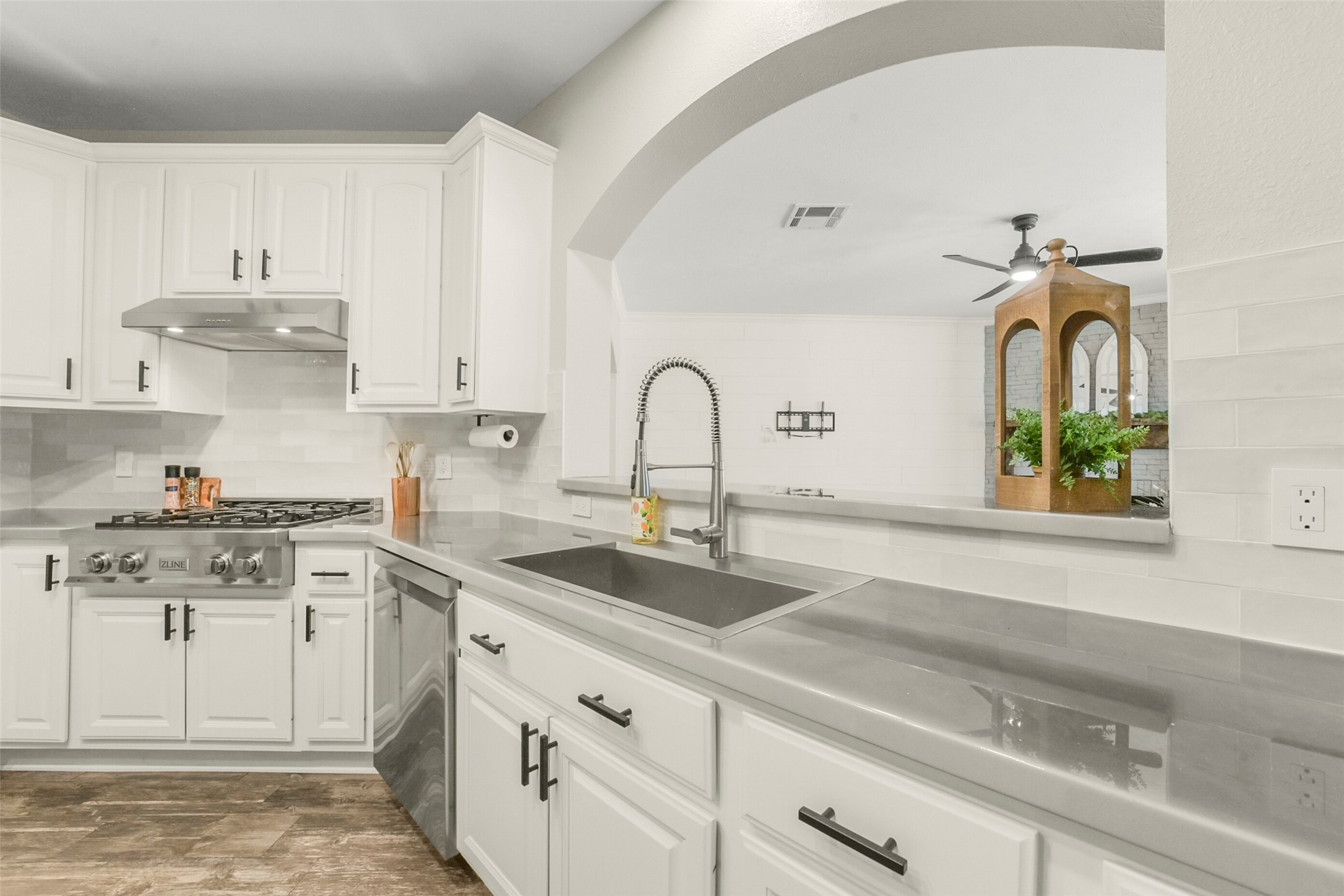 Modern kitchen featuring sleek stainless steel appliances, elegant white cabinetry, and a spacious open layout with a stylish archway.