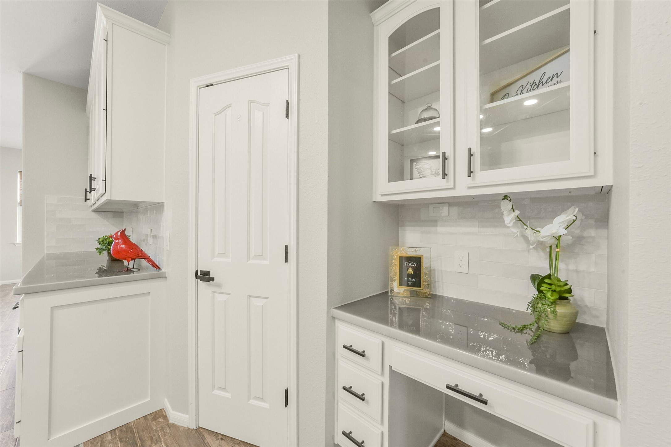 Elegant corner with built-in cabinetry, featuring glass-front upper cabinets and sleek countertops, ideal for organization and display.