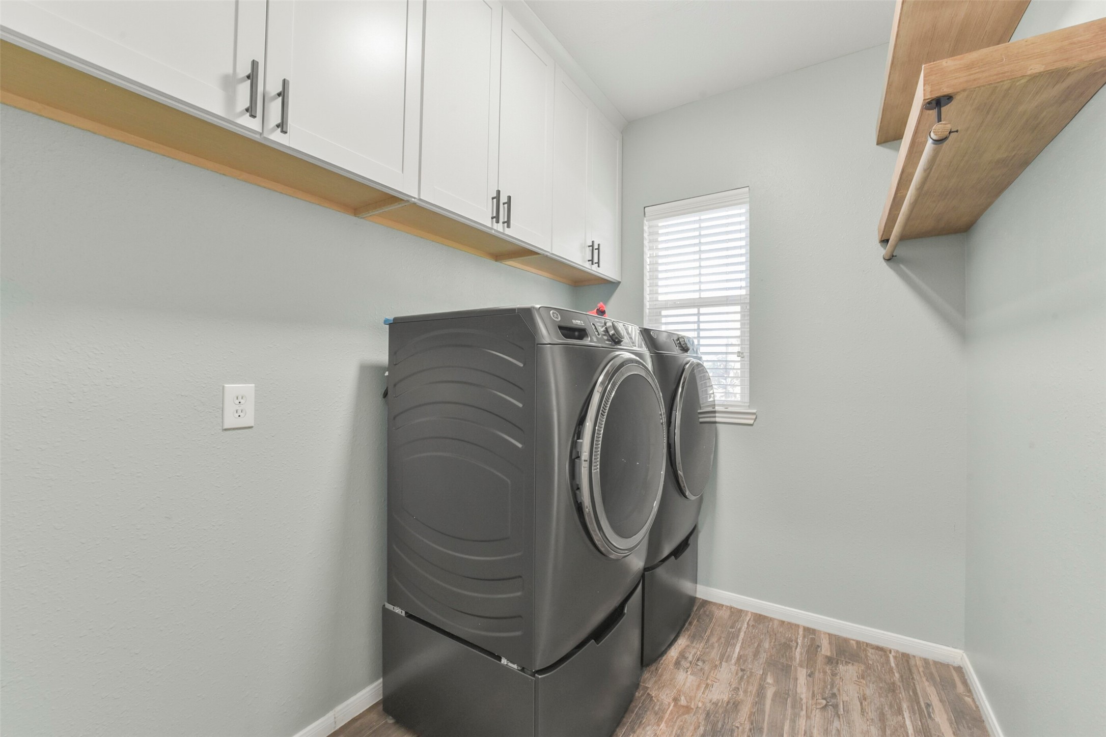 Sleek and functional laundry room with modern appliances, ample cabinetry, and a convenient shelf for additional storage.