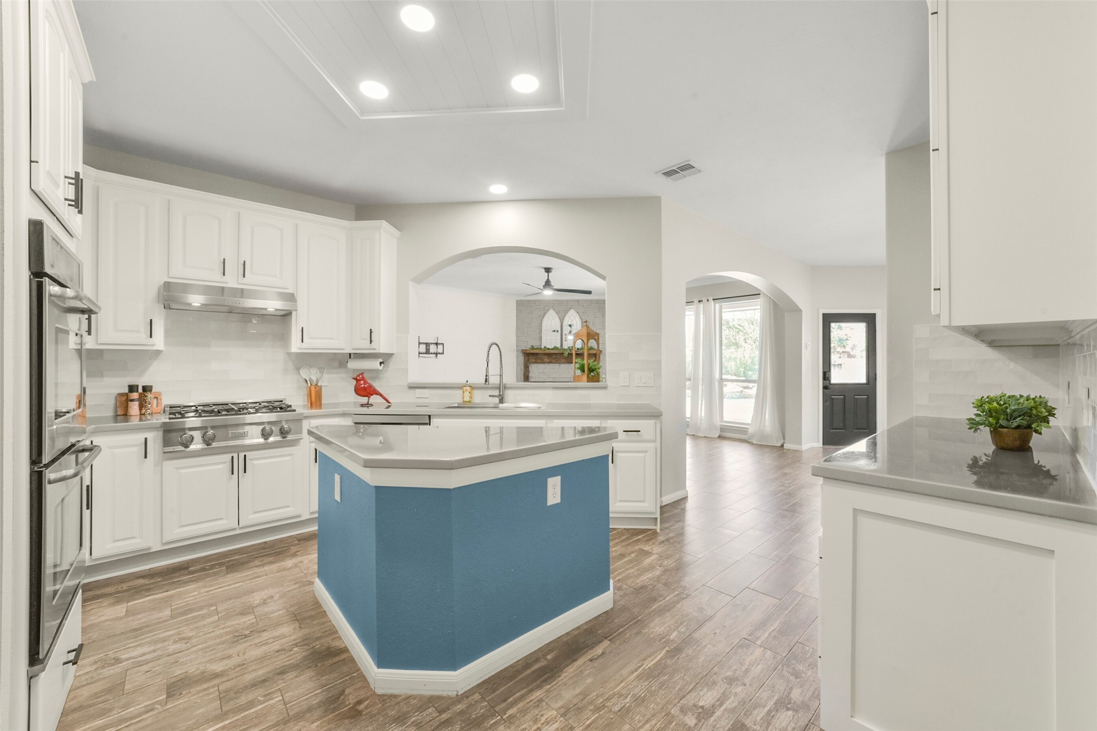 Spacious kitchen featuring sleek white cabinetry, modern appliances, and elegant countertops, accented by warm wood flooring