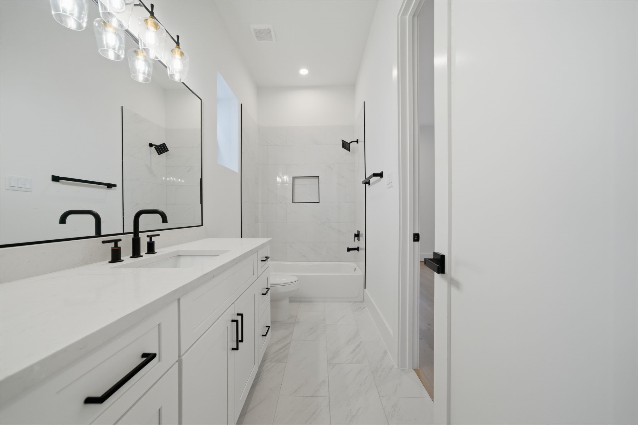 Guest bath #1 with quartz counters, black matte hardware, and plenty of storage and counter space. (Photos are of a previously completed home. Finishes are subject to change.)