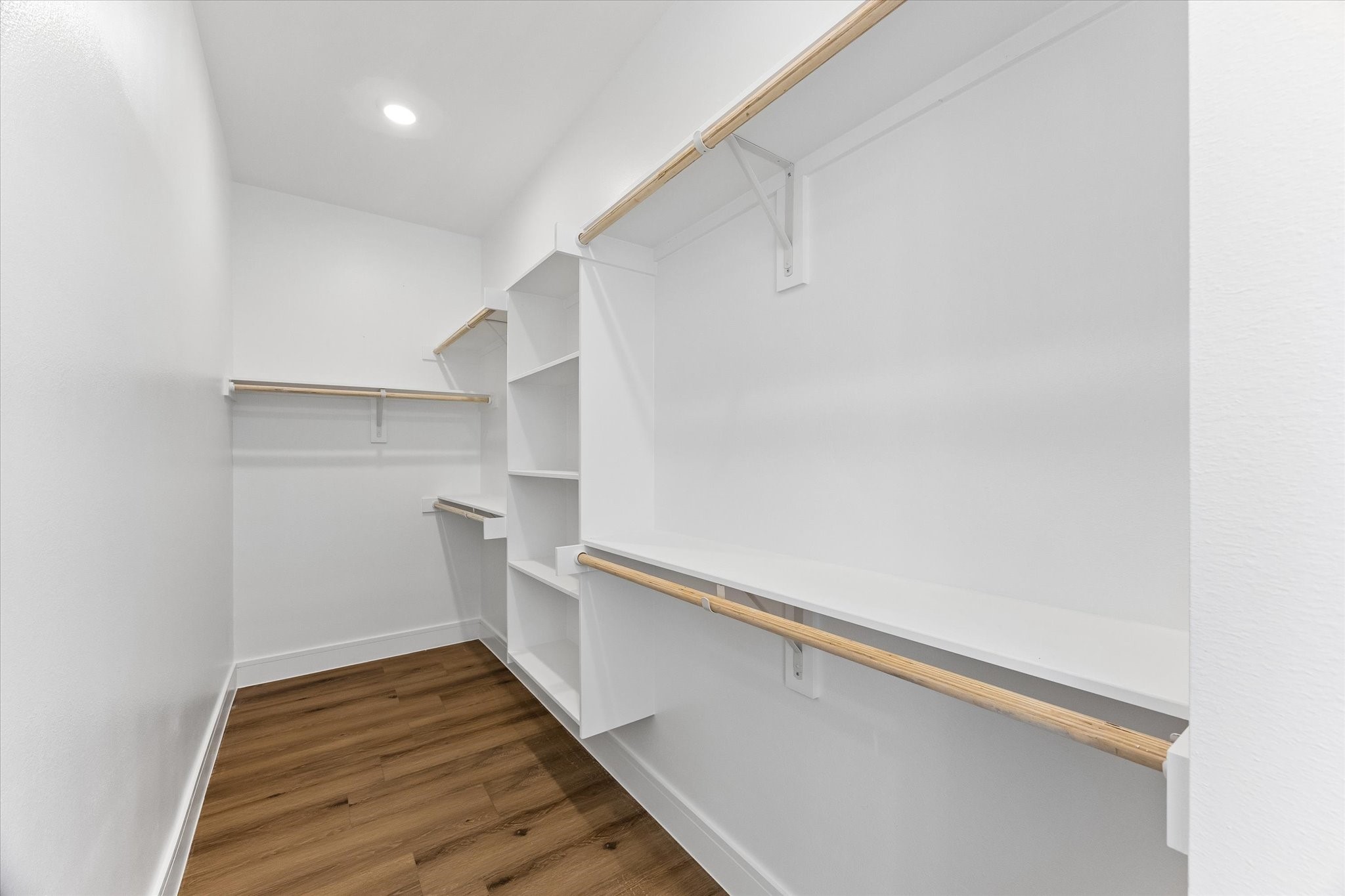 Primary closet with built-in shelving and space for storage.