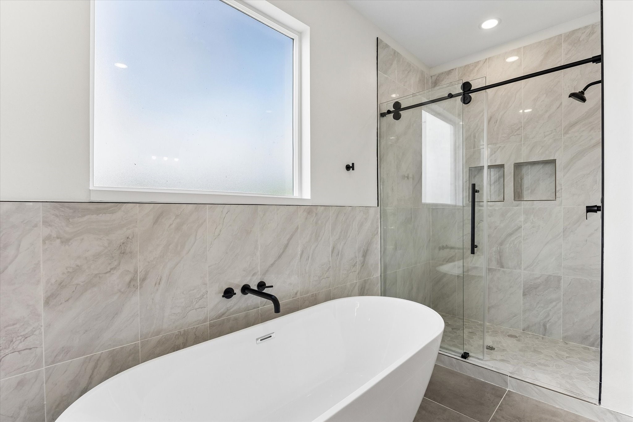Modern bath tub and large shower with seating.