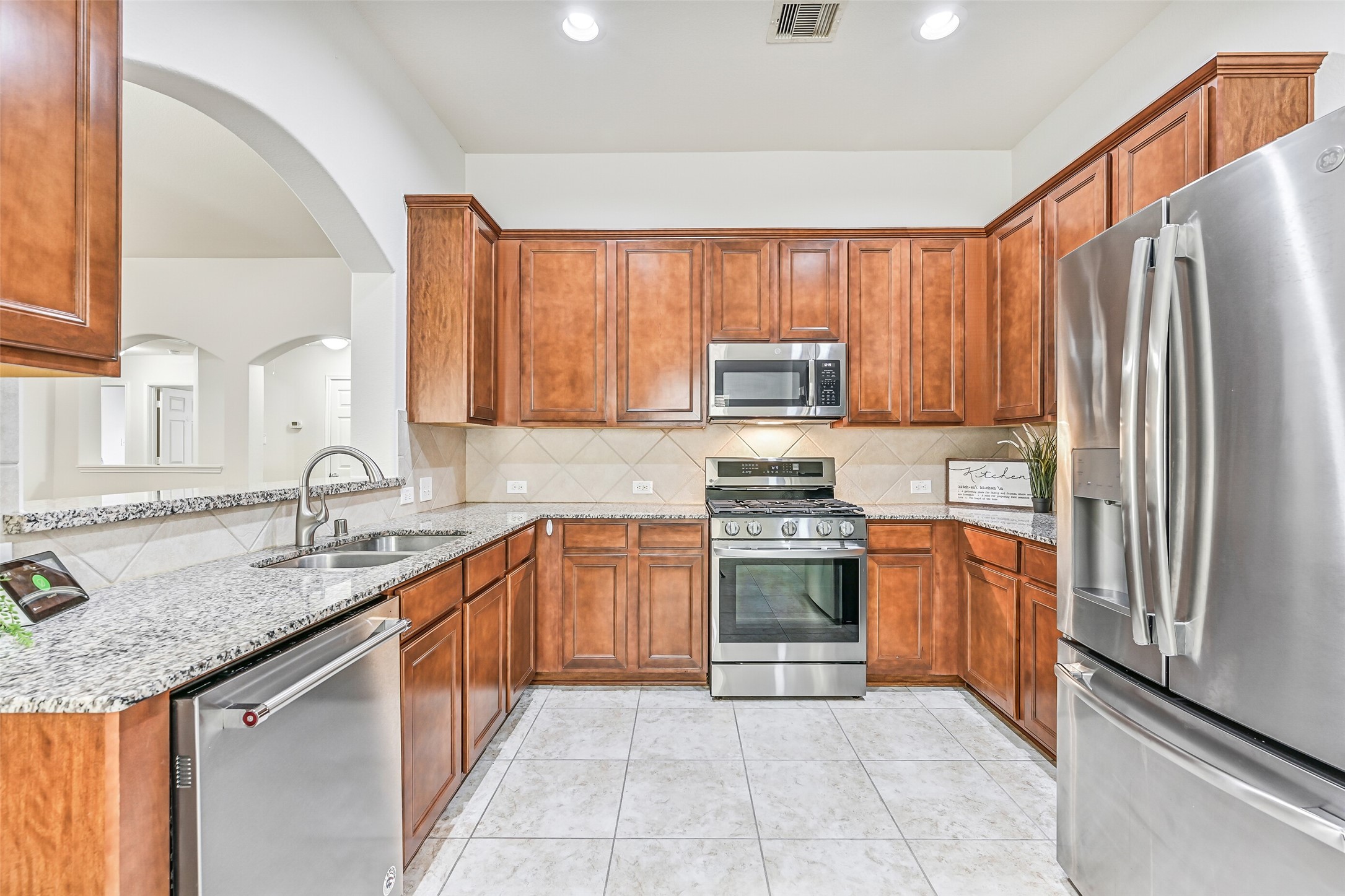 The kitchen offers an impressive amount of cabinetry and counter space, with granite surfaces wrapping around the room, stainless appliances, recessed lighting and an open sightline into the family room.