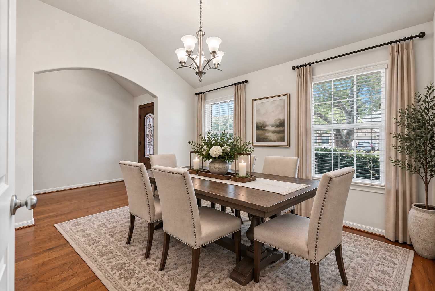 Just off the entry, the spacious formal dining room boasts a dramatic vaulted ceiling, warm wood flooring, fresh neutral paint & a contemporary chrome-finish chandelier, with an oversized arched opening creating an open connection to the foyer. (virtually staged)