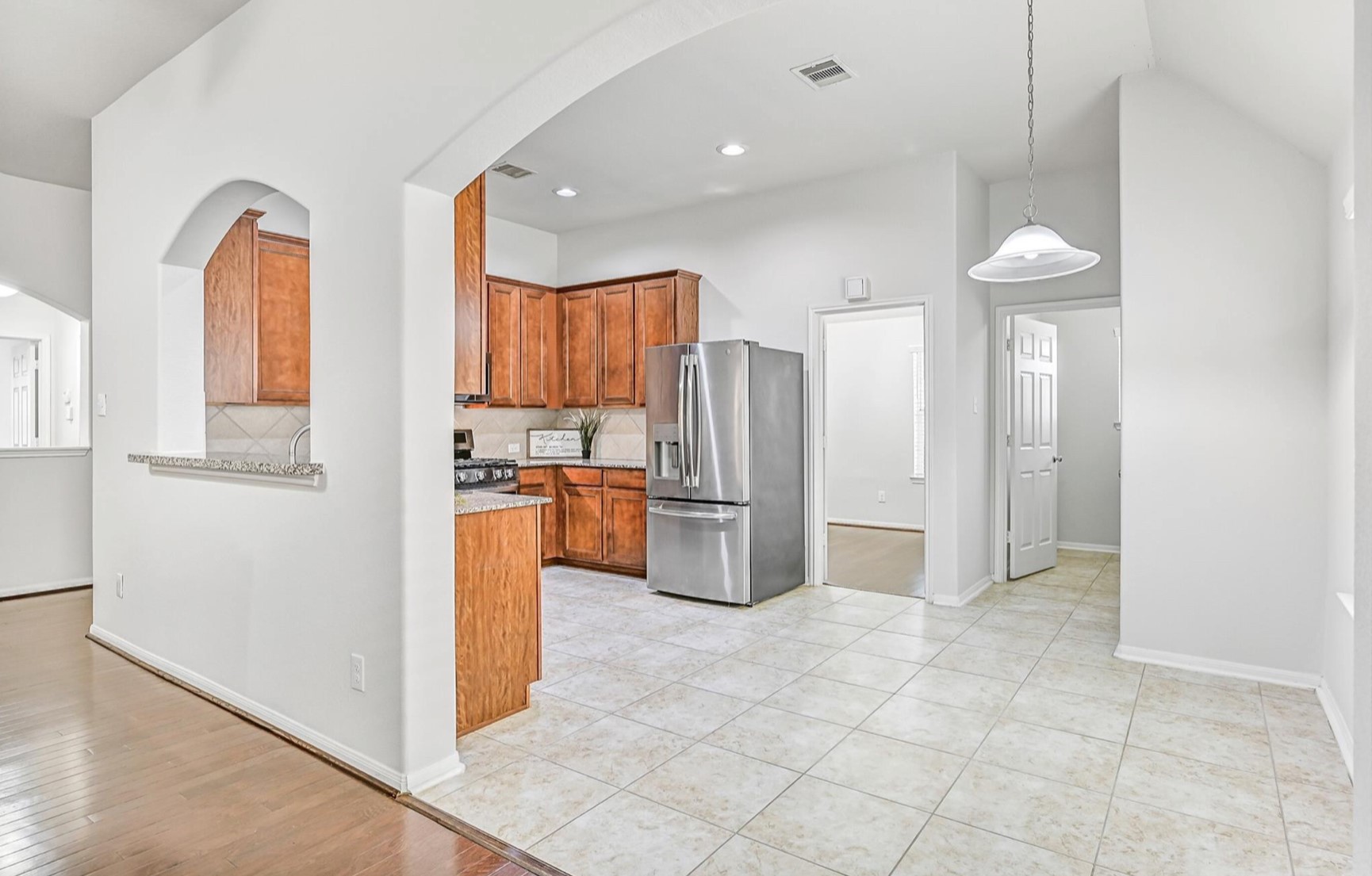 An oversized arched opening introduces the bright breakfast area, conveniently positioned alongside the kitchen and family room with easy-care tile flooring, pendant lighting and plenty of space for a casual dining table.