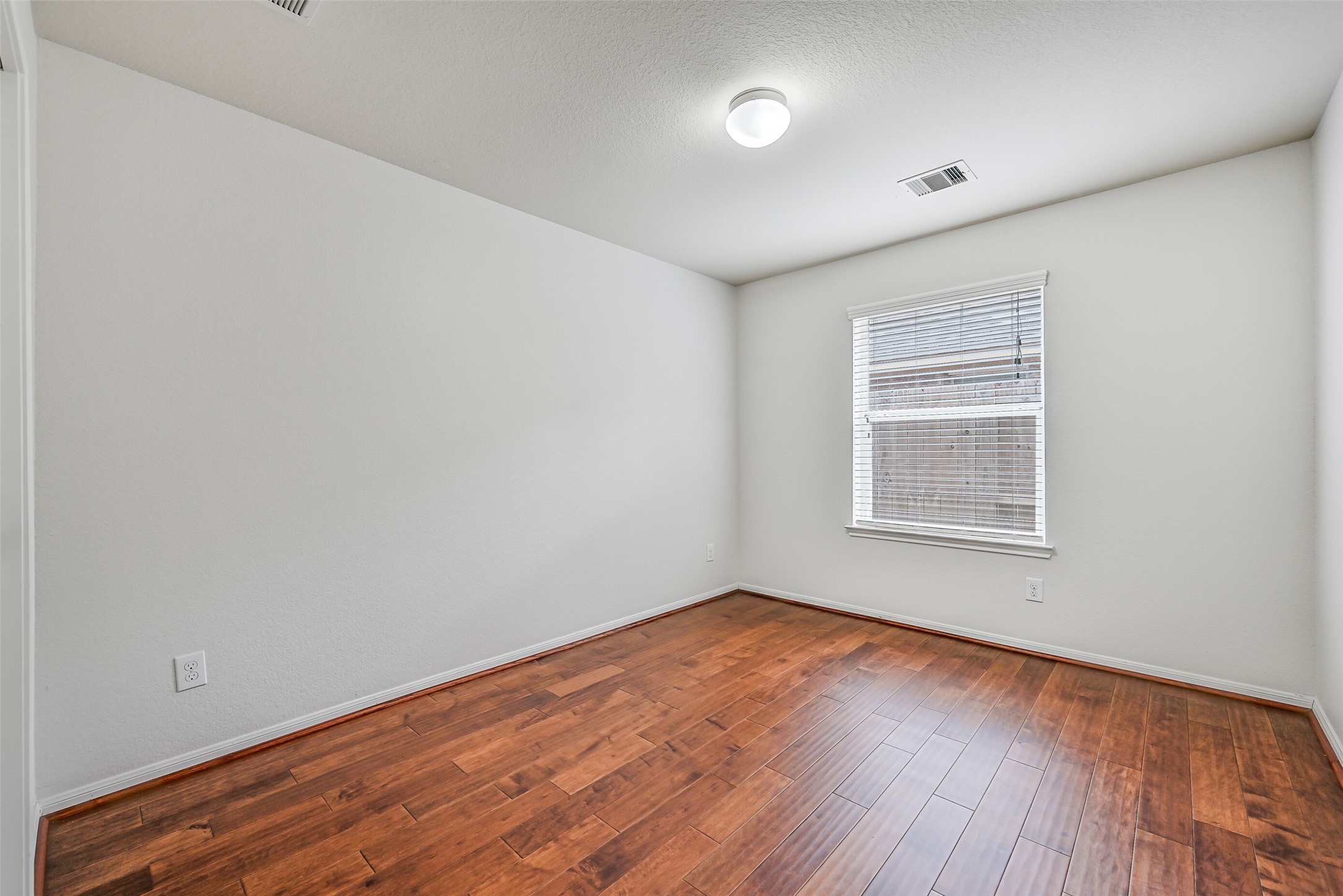 The third secondary bedroom continues the home's cohesive finishes with wood flooring, fresh neutral paint, a large window with 2" blinds & ample wall space for a variety of furniture arrangements.