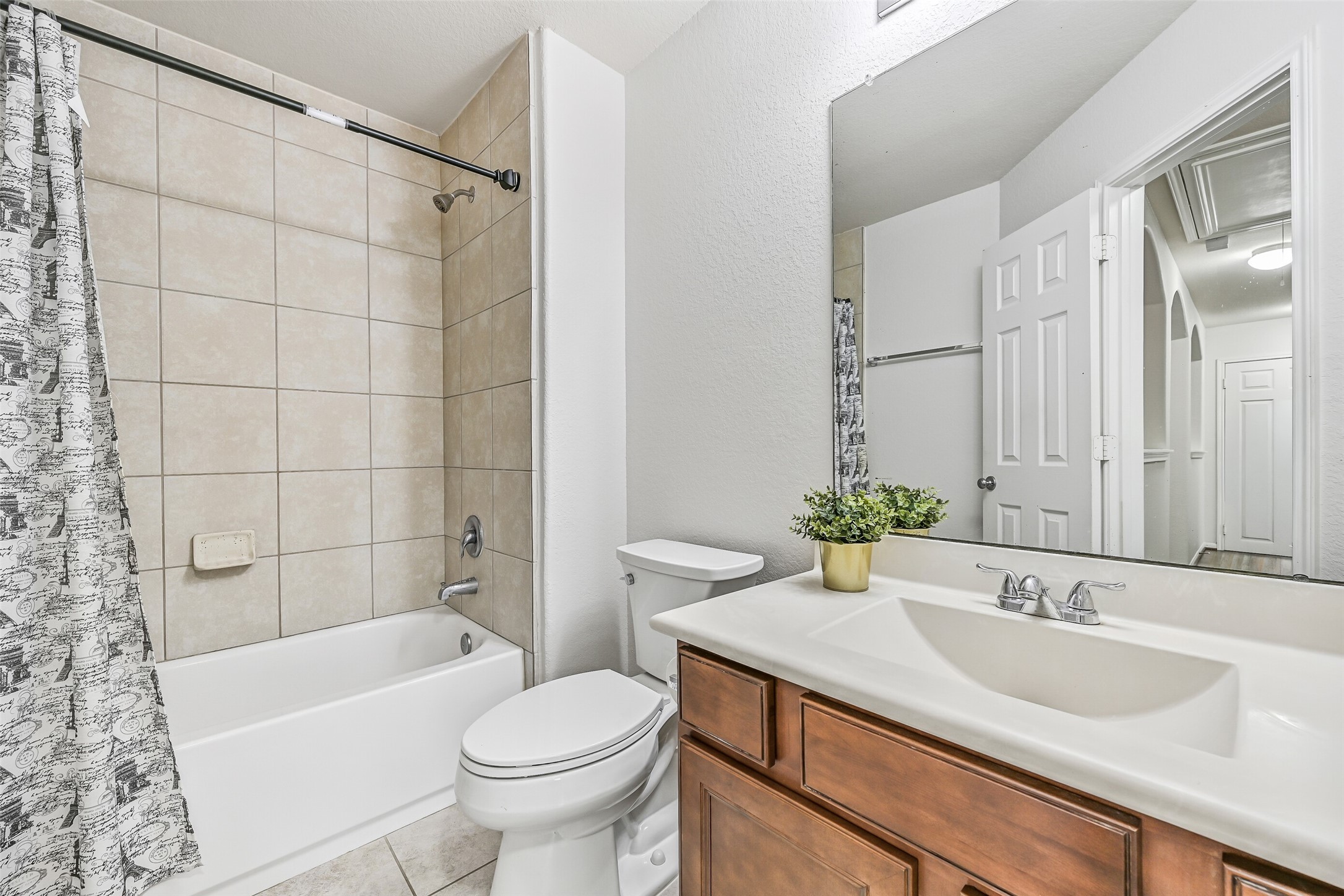 The secondary bedrooms share this well-maintained hall bath featuring tile flooring, a tub/shower combination with full-height tile surround, spacious vanity with storage & an oversized wall mirror.