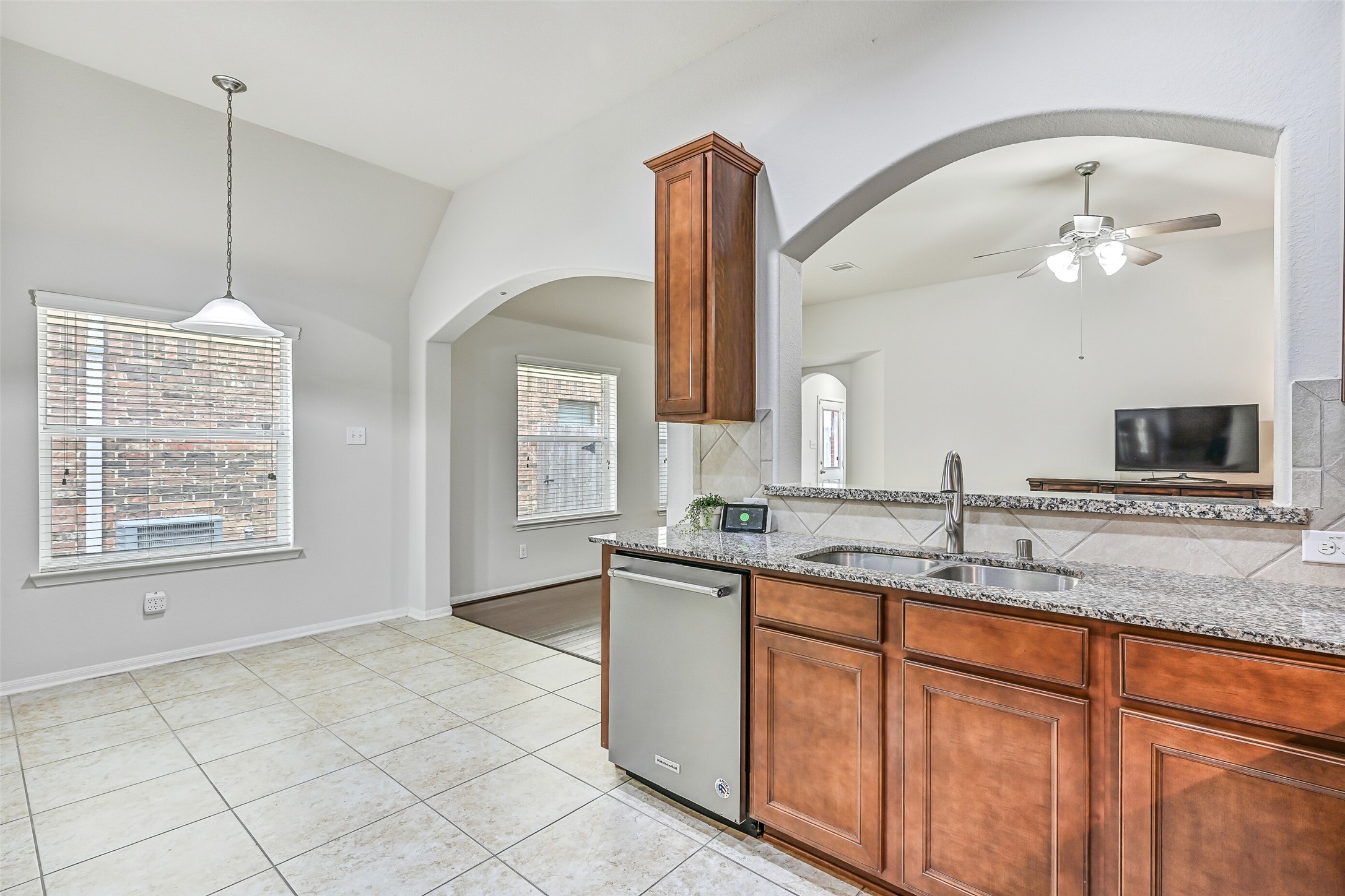 Looking from the kitchen toward the breakfast area, granite counters and a raised serving bar overlook the family room, creating an open layout that keeps the kitchen connected to both dining and living spaces.