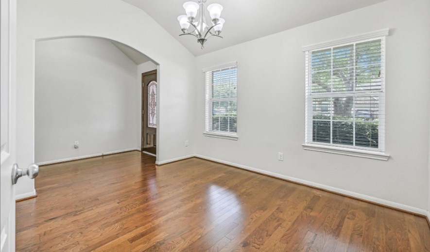 Just off the entry, the spacious formal dining room boasts a dramatic vaulted ceiling, warm wood flooring, fresh neutral paint & a contemporary chrome-finish chandelier, with an oversized arched opening creating an open connection to the foyer.