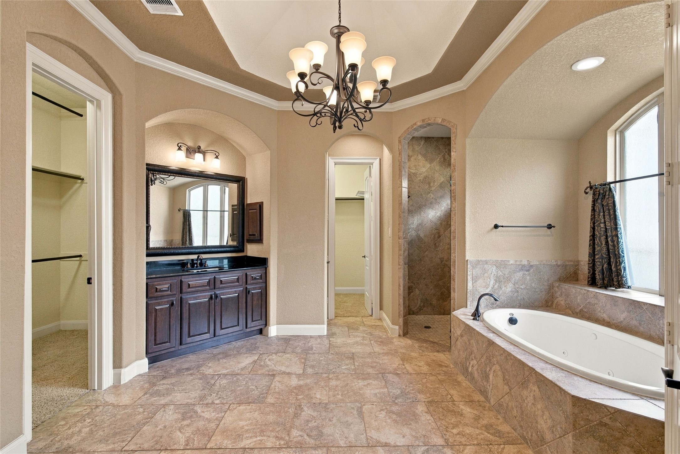 Luxurious primary bathroom featuring an oversized jetted soaking tub, separate walk-in shower, and beautiful architectural details.