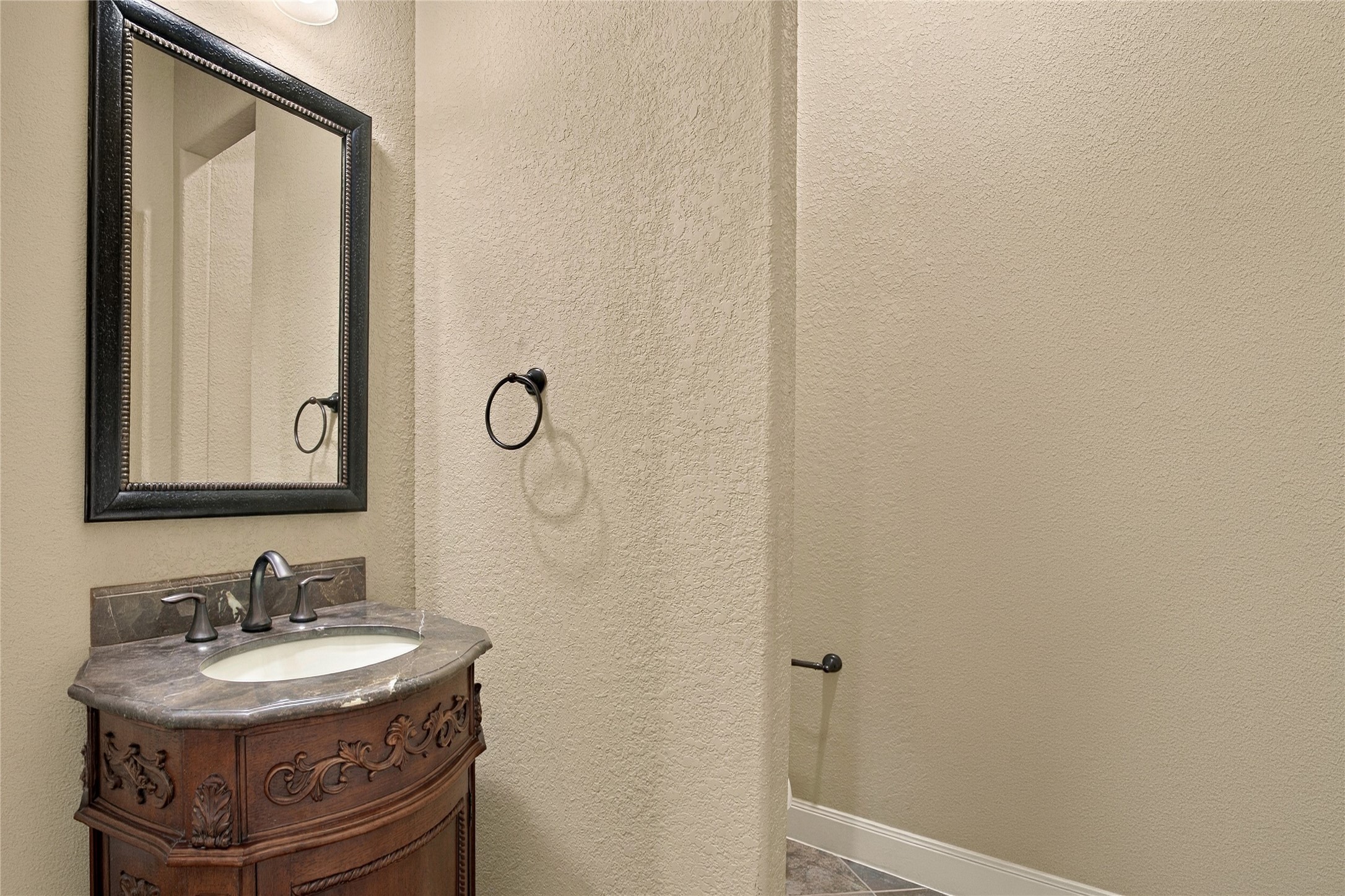 Convenient downstairs half bathroom featuring a decorative vanity and framed mirror.