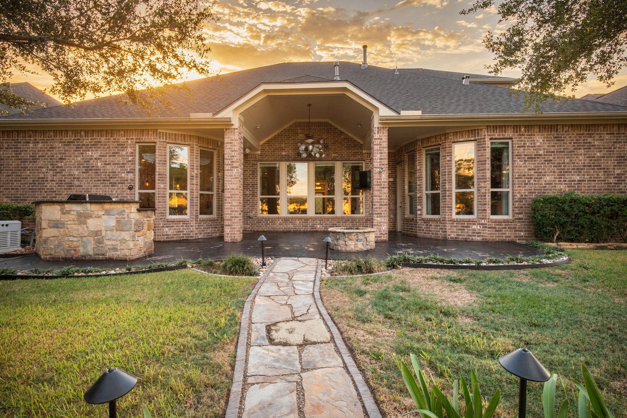 Beautiful rear exterior showcasing the expansive covered patio, large windows, and landscaped backyard, all highlighted by gorgeous sunset views that create a truly breathtaking setting!