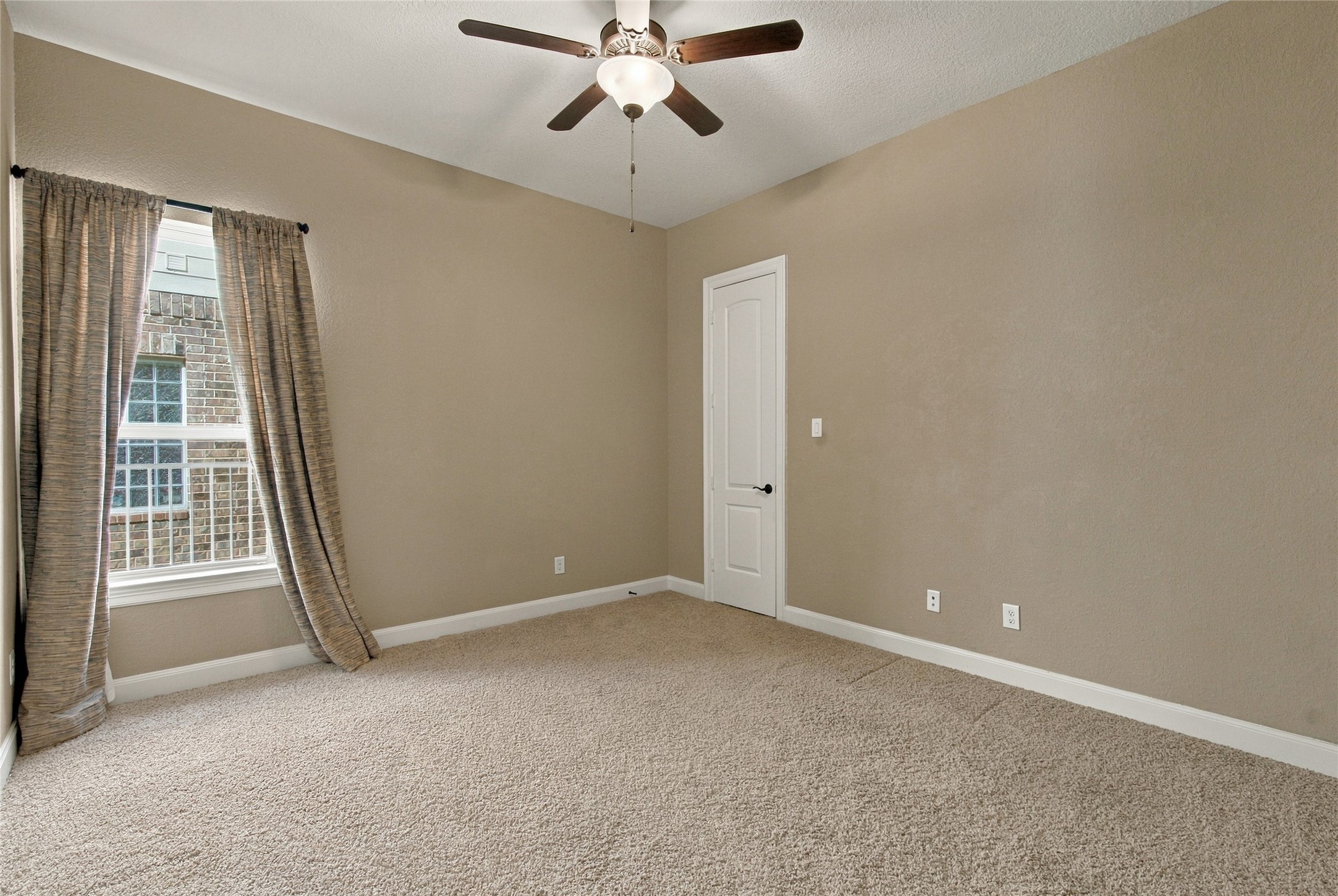 Spacious secondary bedroom featuring plush carpeting, a walk-in closet, and a large window allowing natural light to fill the space.
