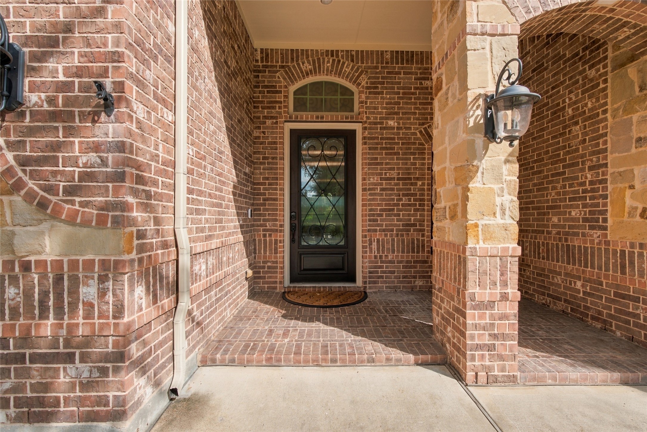 Welcoming covered front porch with charming brick detailing and an inviting entryway.
