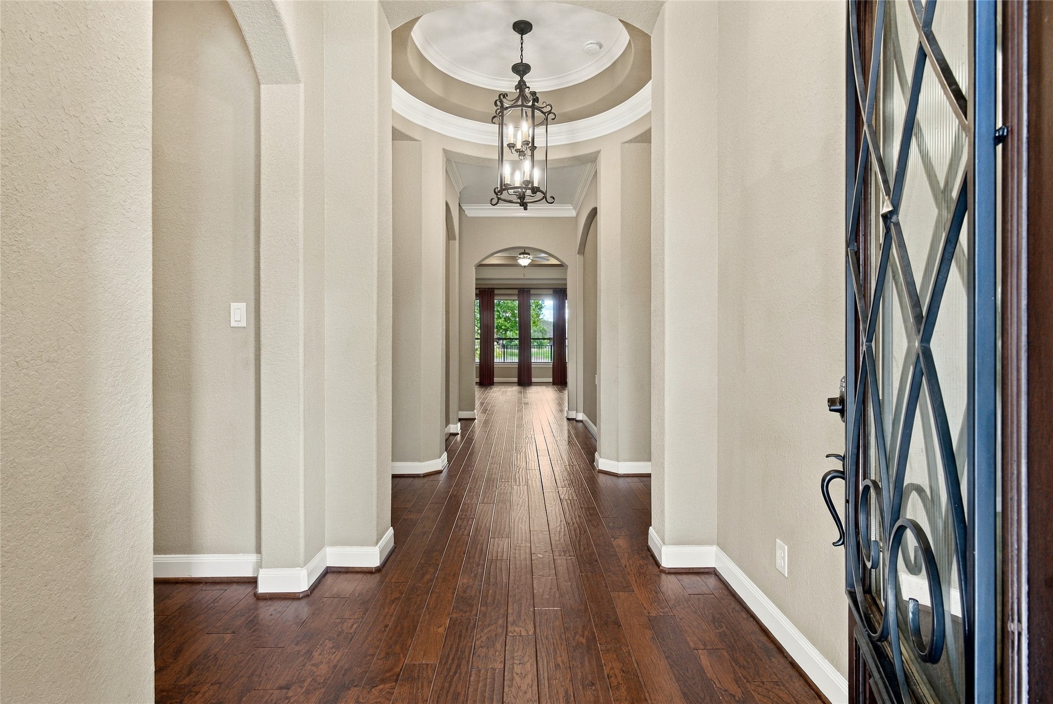 Elegant entryway featuring wood flooring, high ceilings, beautiful architectural details, and a stylish chandelier.