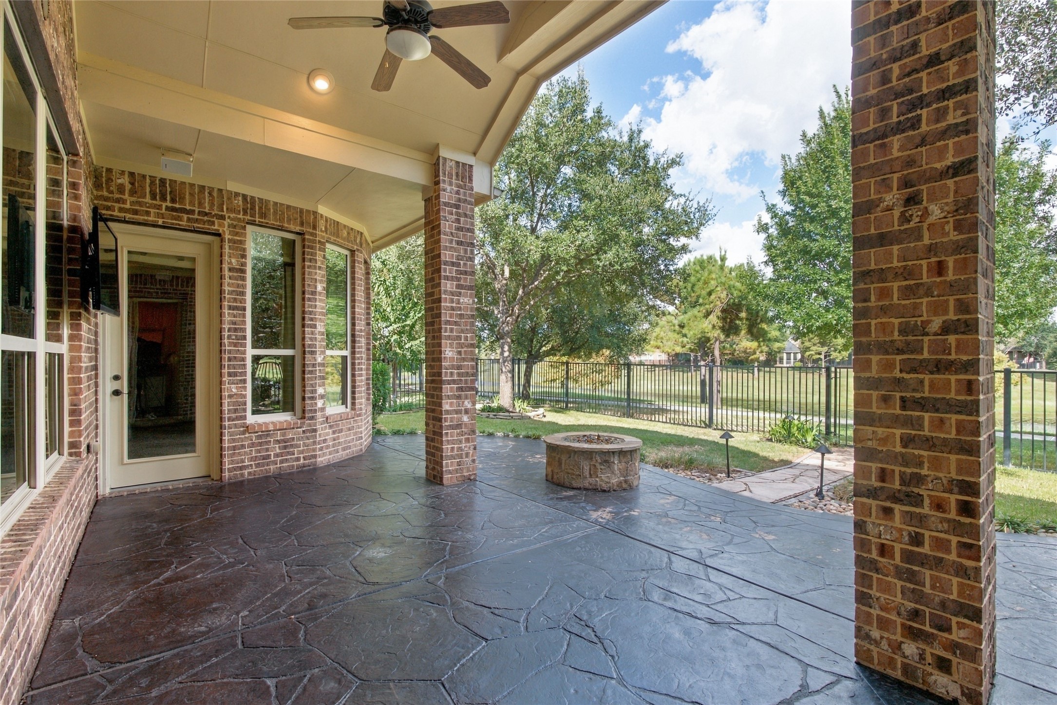 Expansive covered patio featuring ceiling fans, outdoor speakers, and a gas fire pit. This inviting outdoor space is perfect for relaxing or entertaining while enjoying beautiful waterfront views.