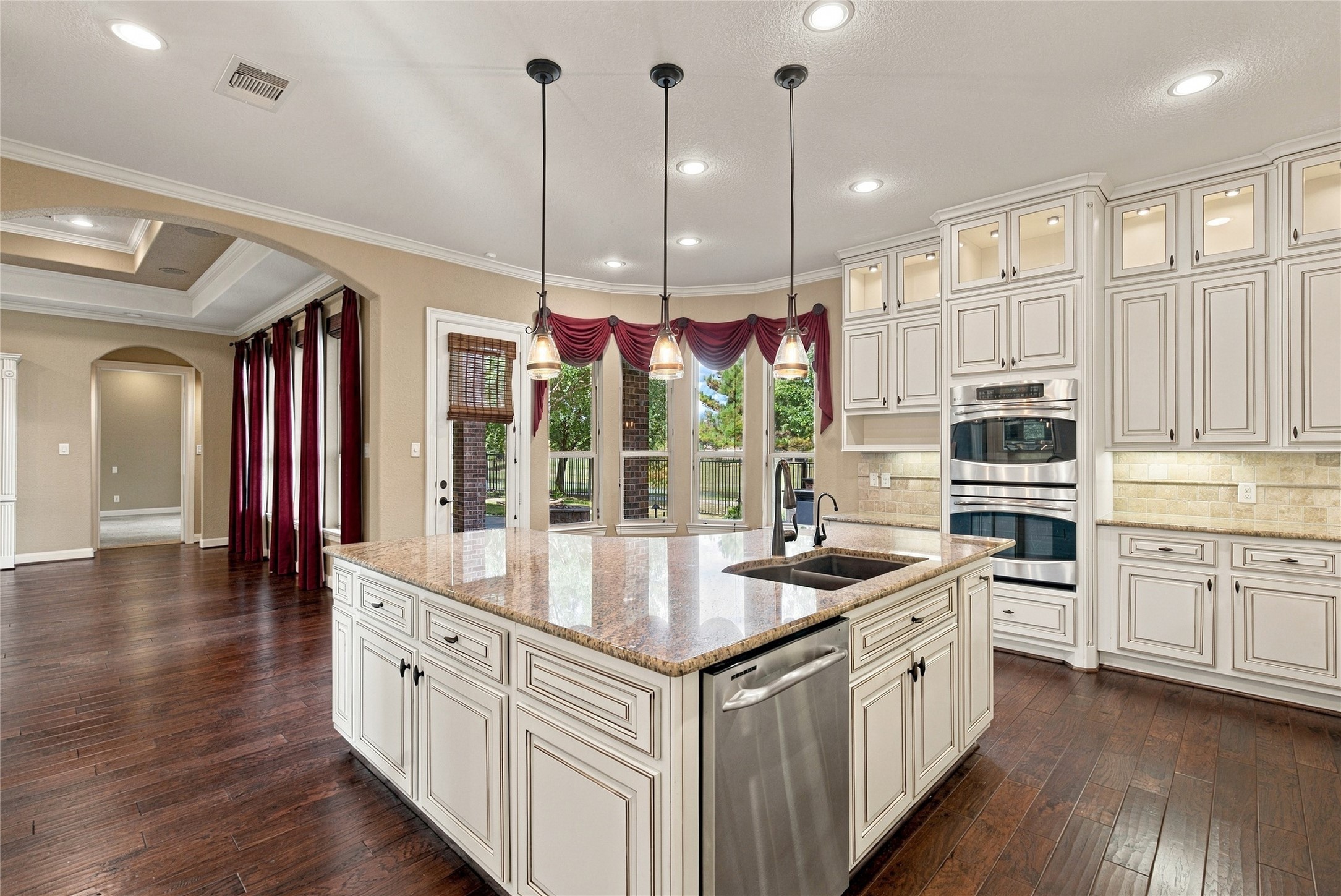 Another view of the impressive kitchen showcasing the spacious center island, pendant lighting, double ovens, and abundant cabinet storage.