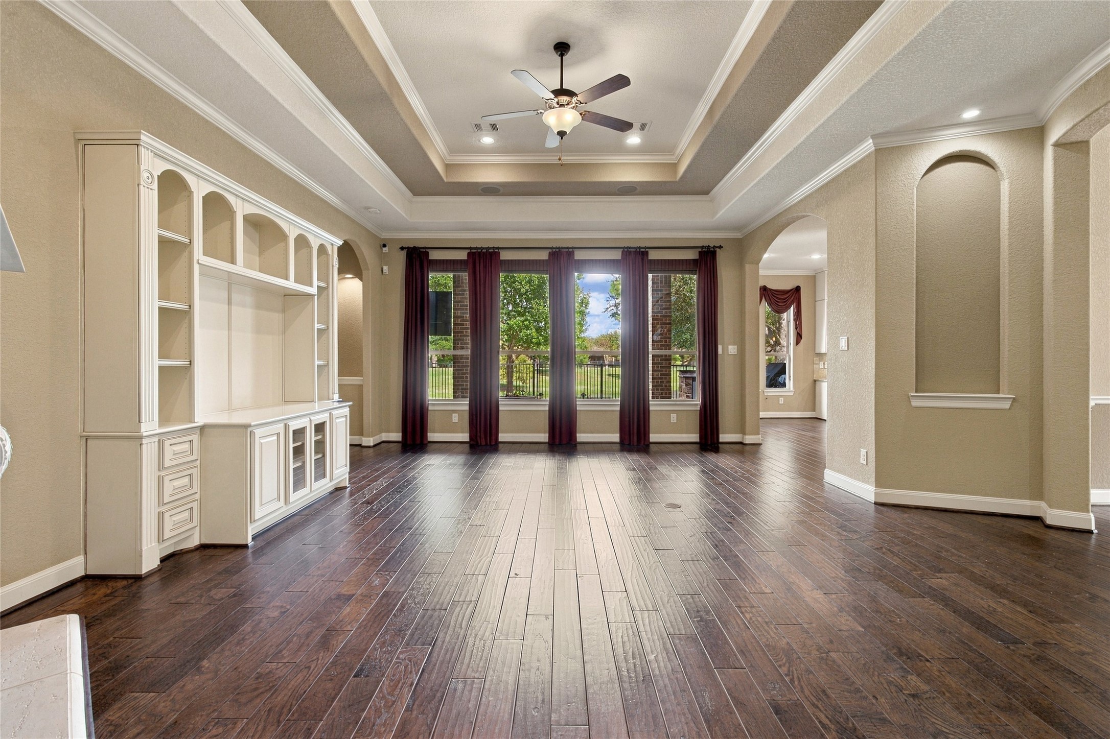 Another view of the inviting living room showcasing the open layout, decorative ceiling details, and large windows overlooking the backyard.