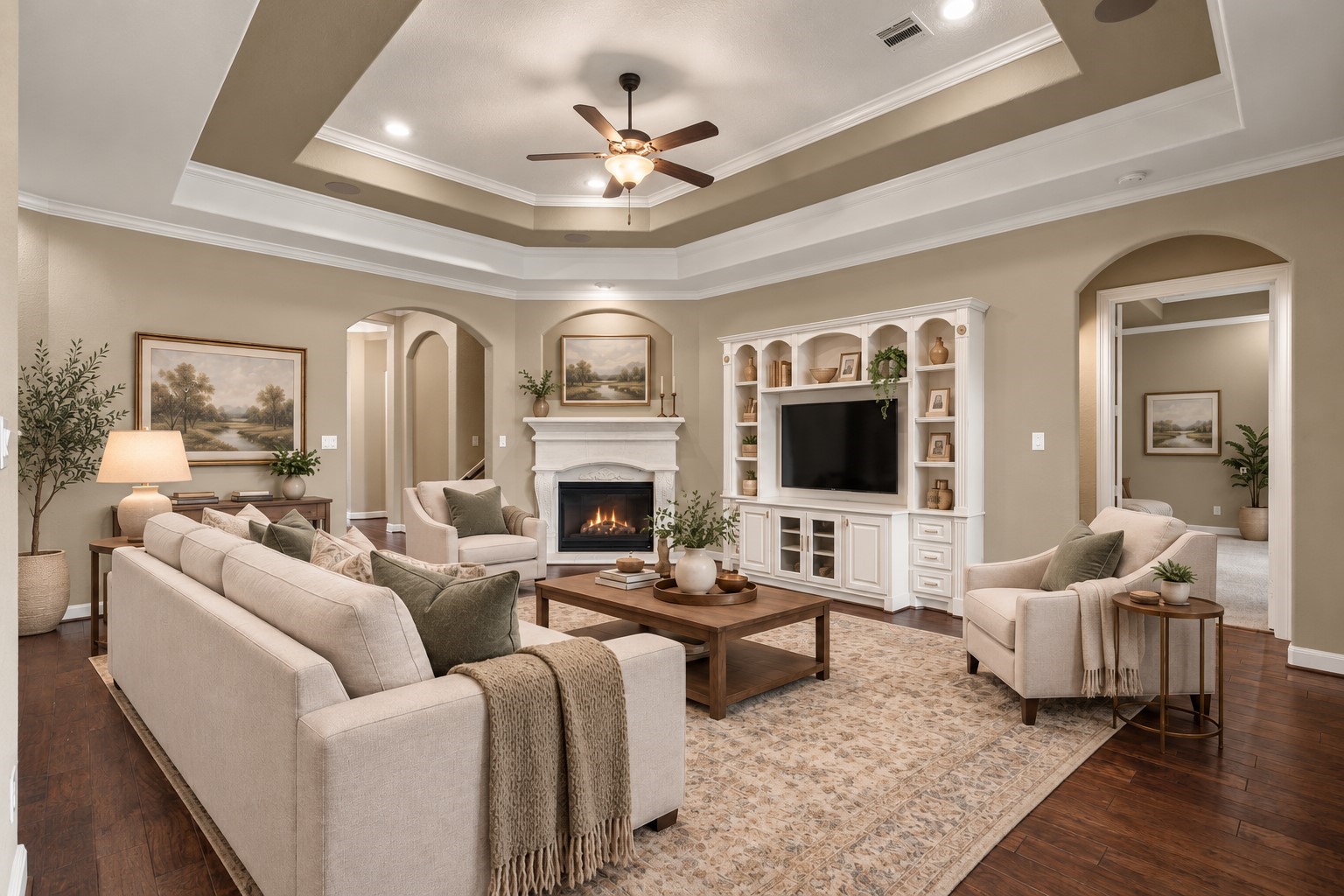 Spacious living room featuring beautiful wood flooring, a fireplace, custom built-ins, and an elegant tray ceiling. (Virtually Staged)