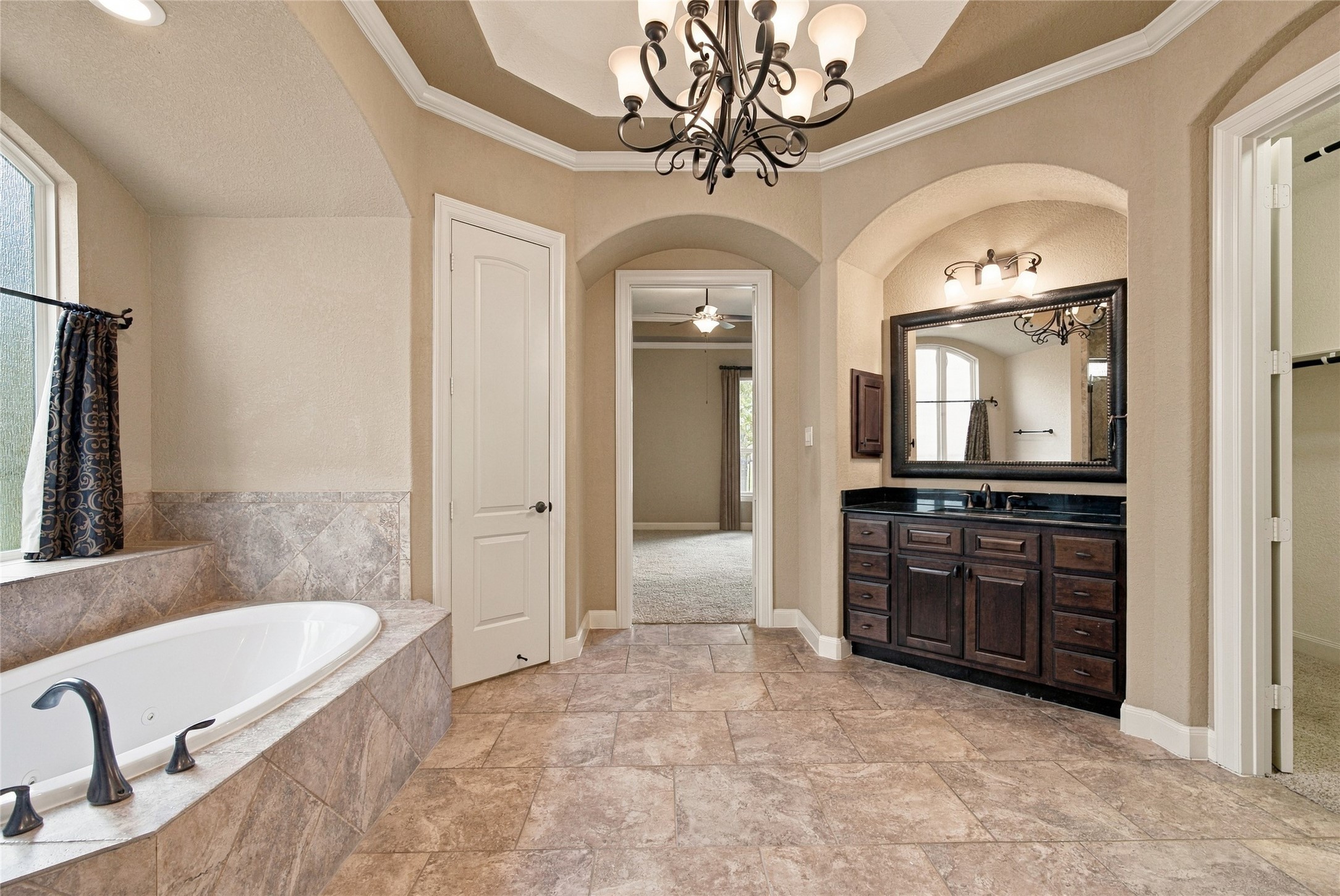 Enjoy a relaxing retreat in the spacious primary bathroom featuring an oversized jetted tub, separate shower, and beautiful chandelier.