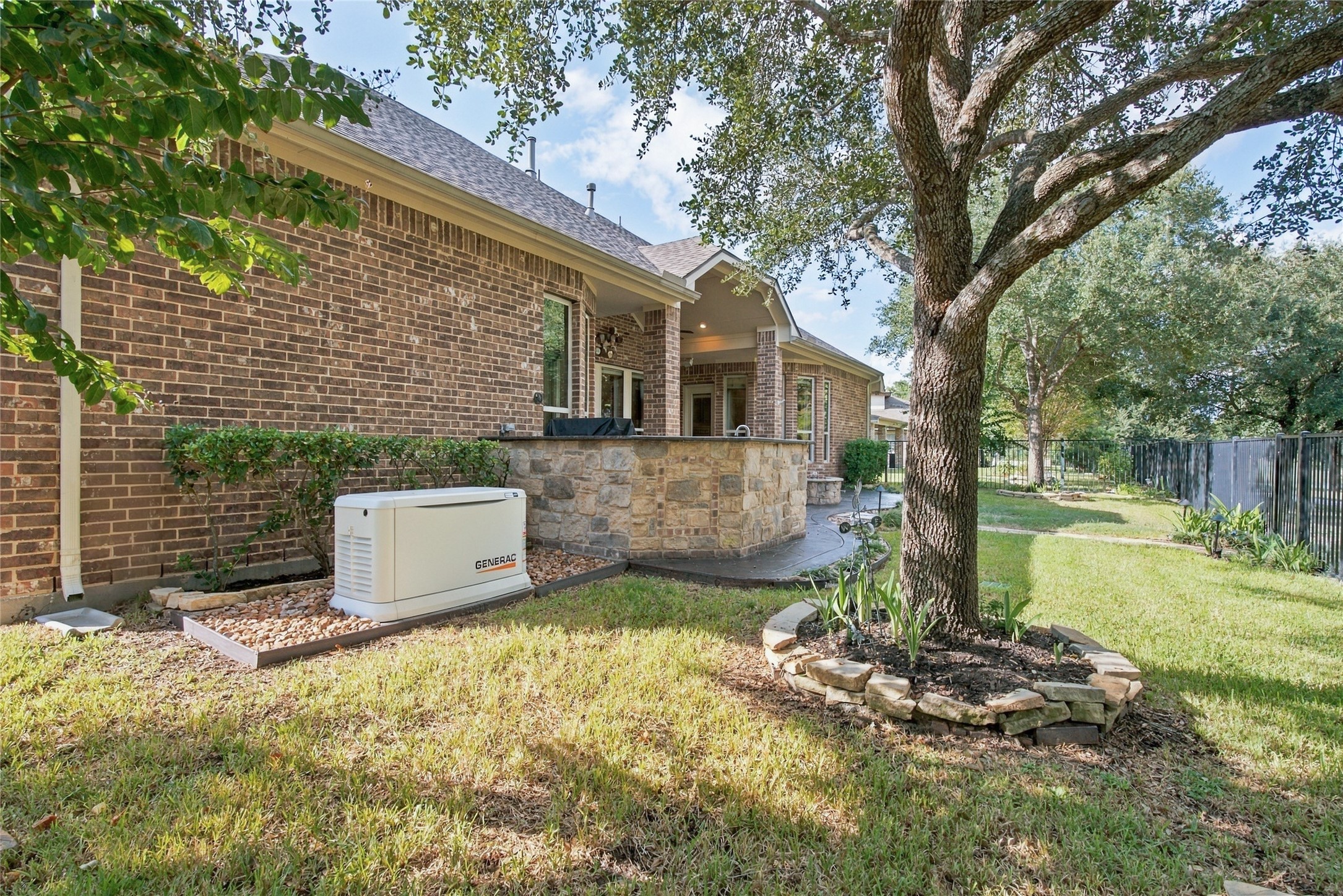 Additional backyard view highlighting the attractive landscaping, outdoor entertaining space, and whole-home generator.