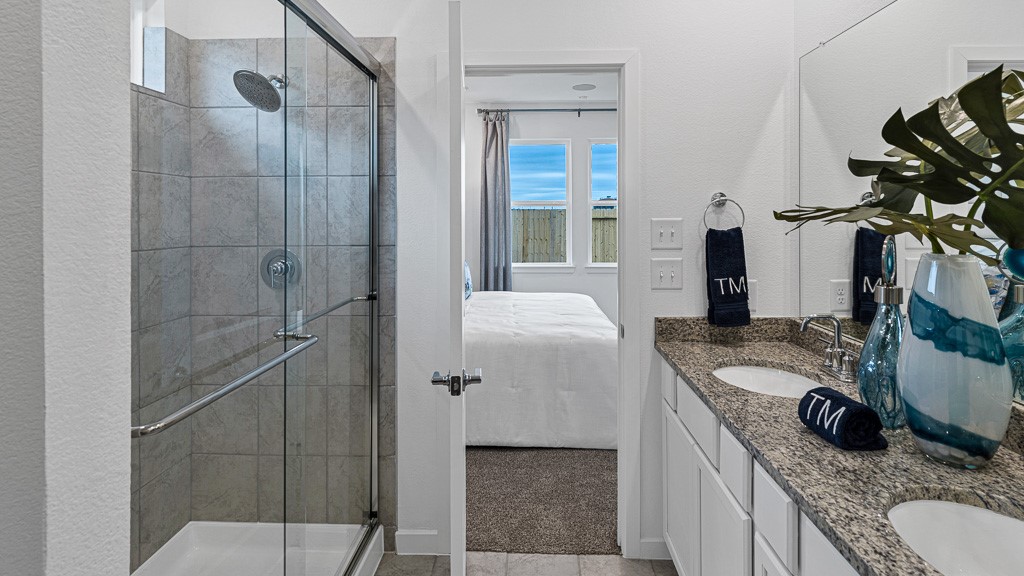 Primary ensuite bath has double vanities and a walk-in shower with glass enclosure.