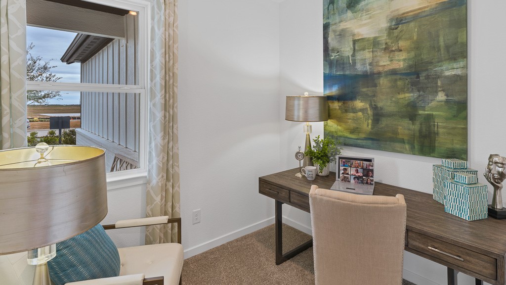 Upfront home office has gorgeous window with custom drapery.