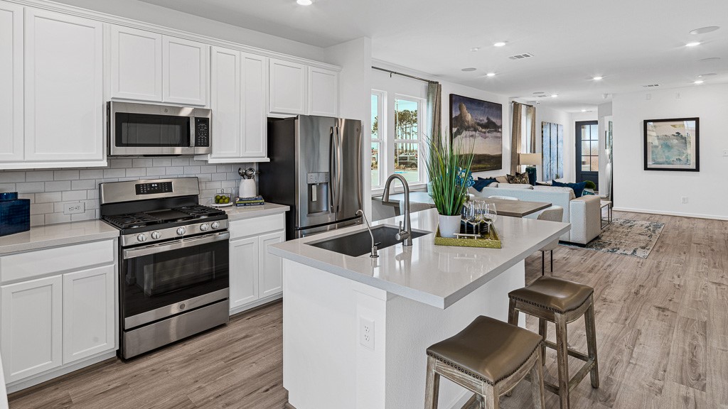 Island has stainless steel sink with modern fixtures, filtered water faucet, dishwasher and room for seating.