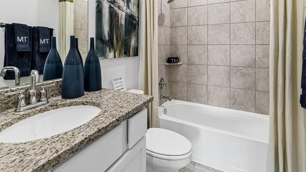 Bathroom 2 has a modern single vanity with silver fixtures, and granite counters, with a tub/shower combo.